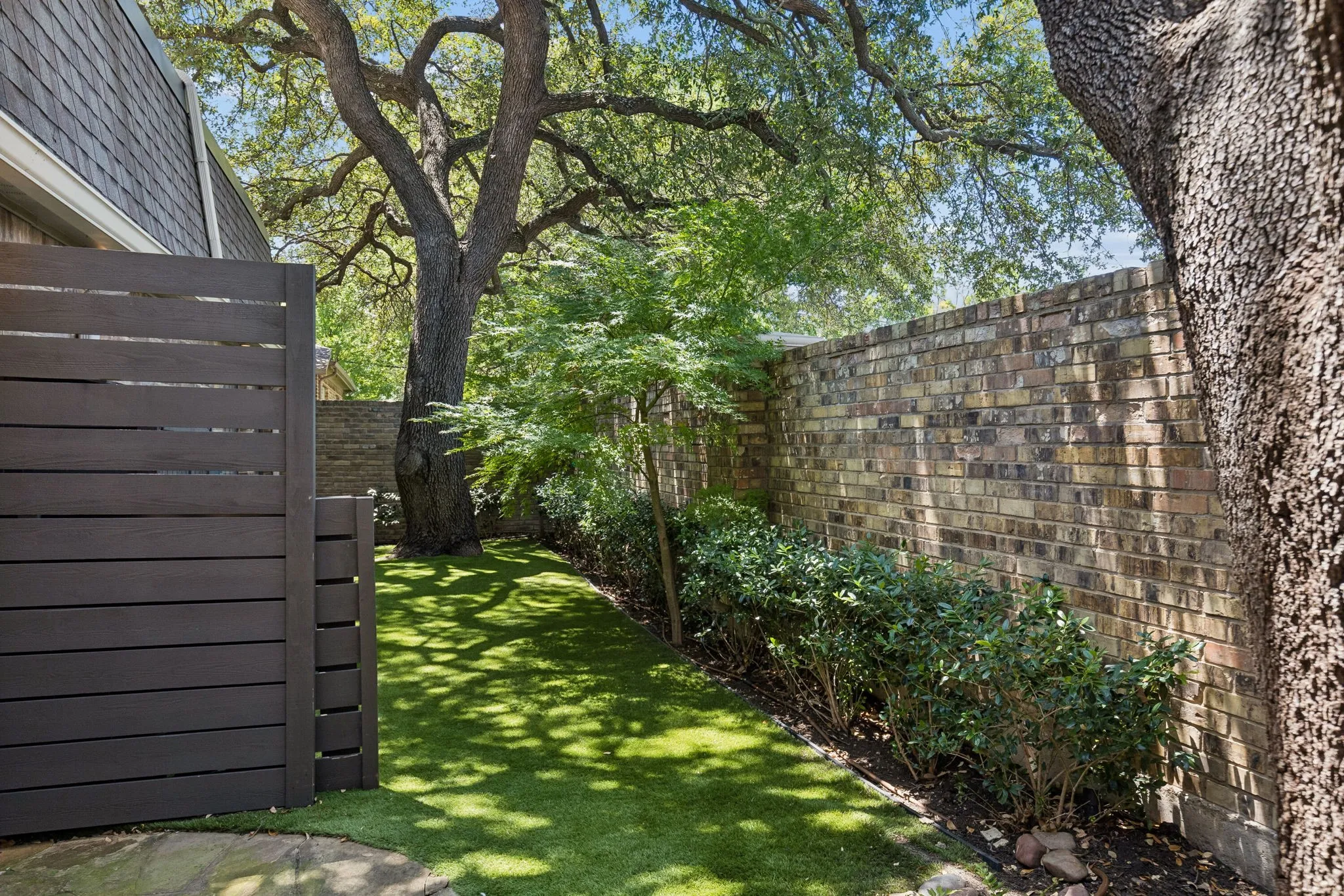 Sprawling oak trees, turfed yard, and lush landscape.