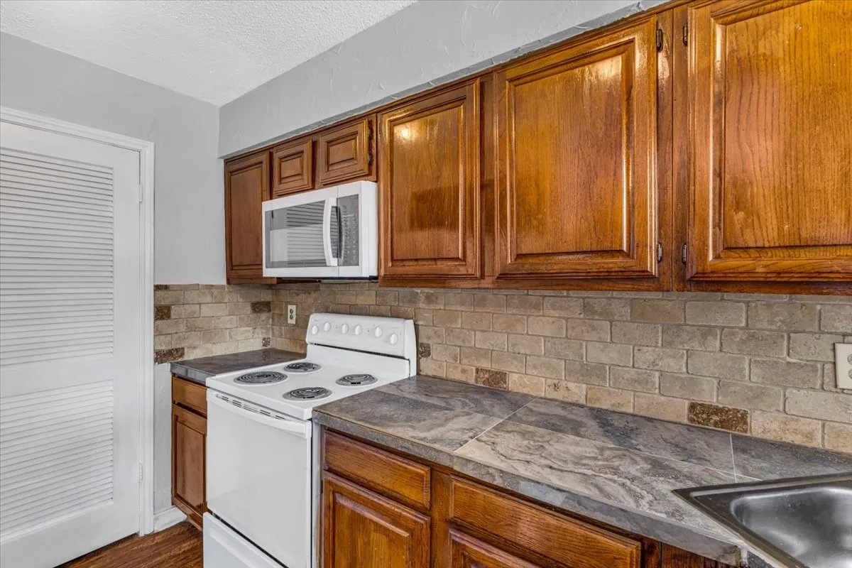 Warm wood cabinetry with raised-panel doors and stainless steel microwave above the range.