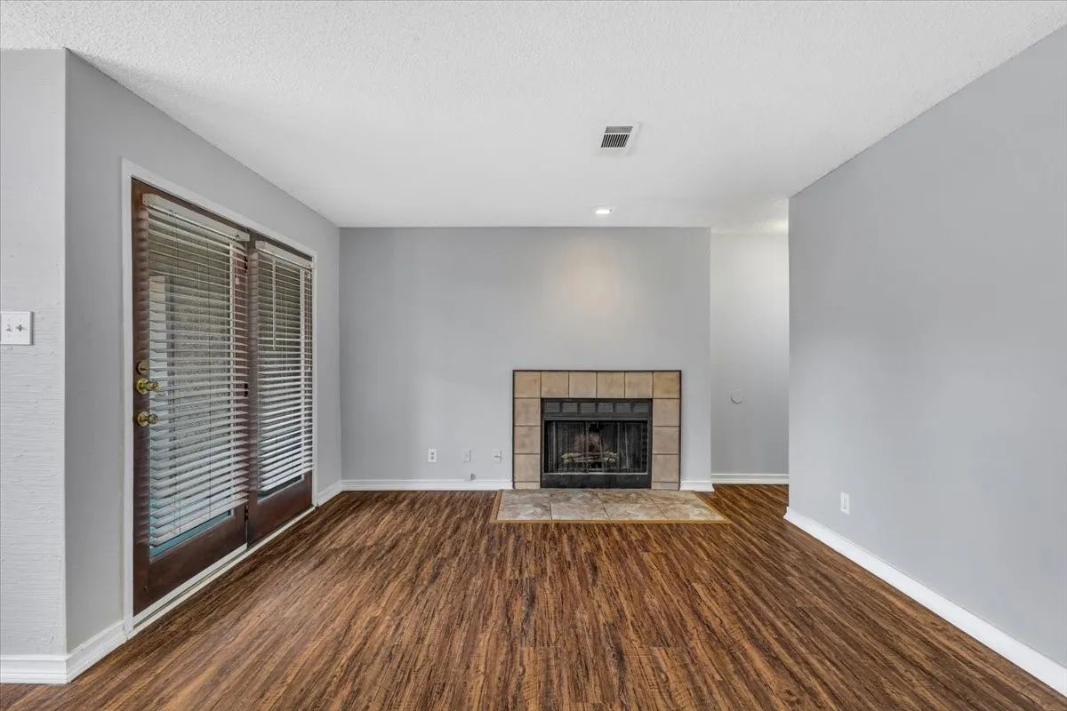 Wood-finish flooring, tiled fireplace with hearth, and double glass-paneled doors.