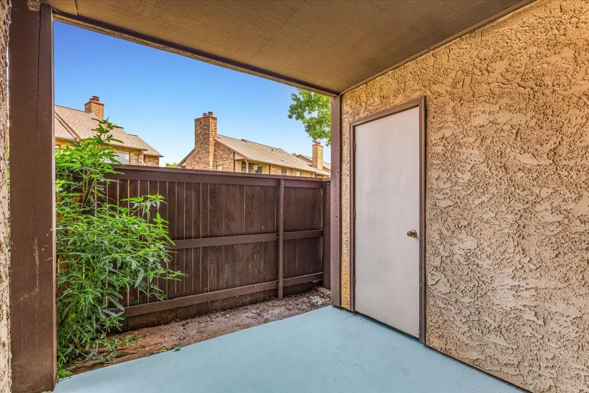 Covered patio with stucco-finish walls and light blue polished concrete flooring.