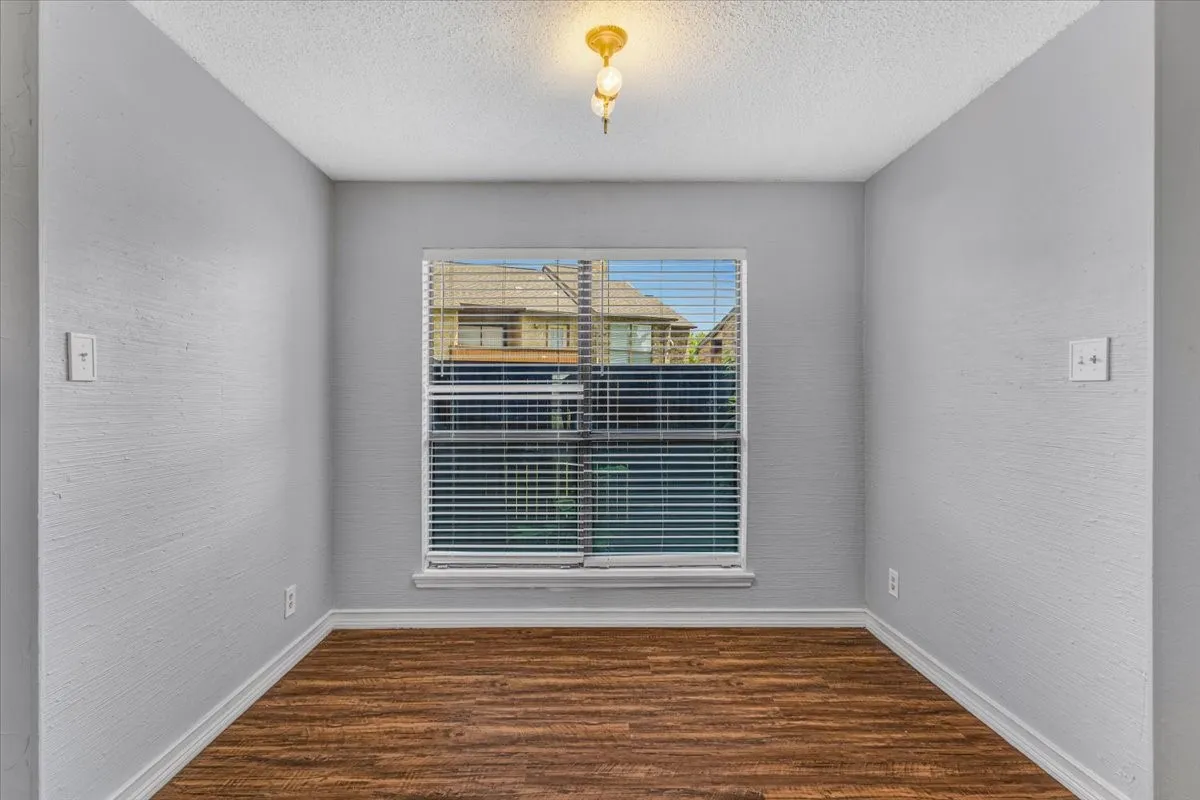 Wood-finish flooring, with a large window with blinds.