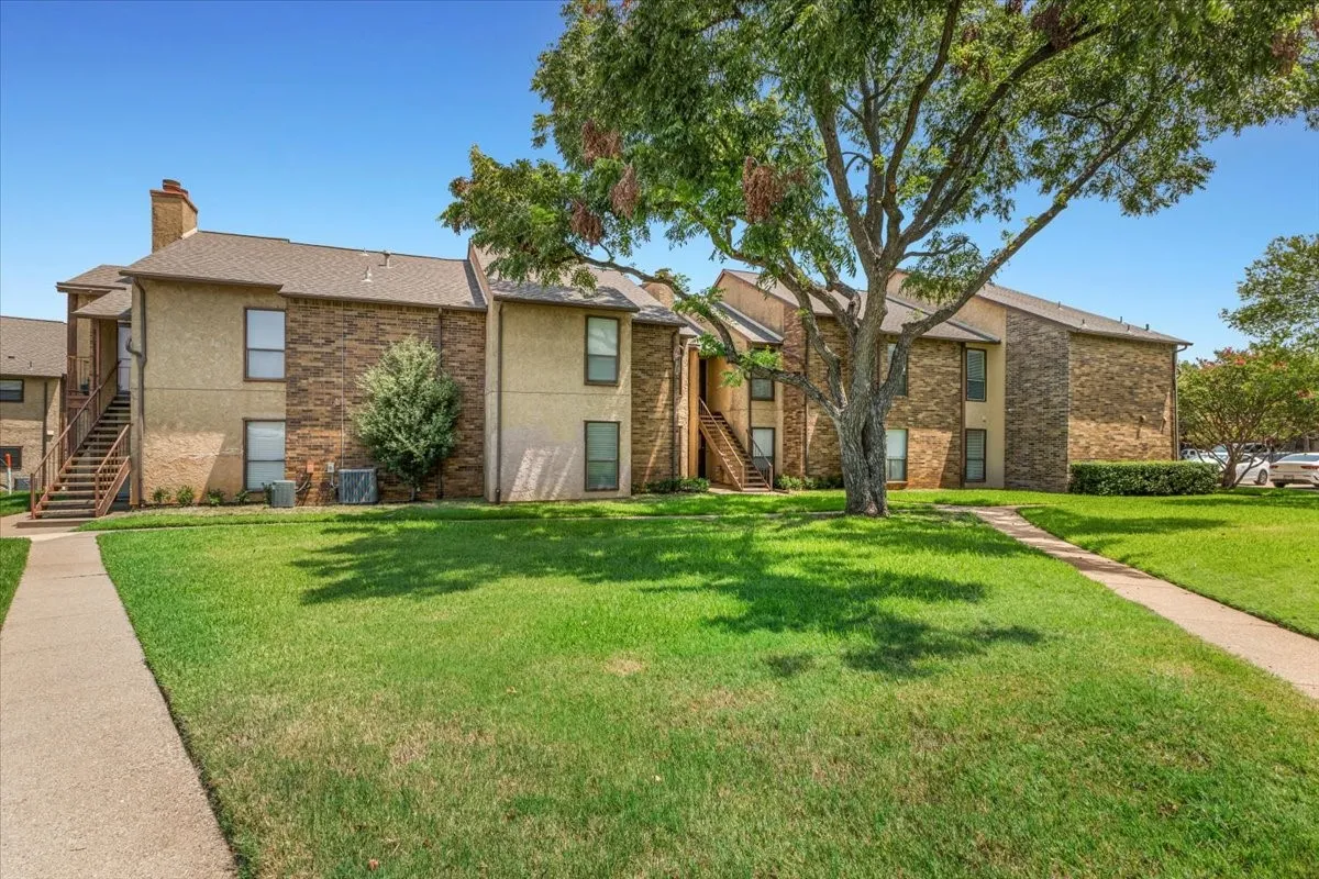 First Floor Condo in a Two-story building featuring brick and stucco exterior, and a central outdoor staircase.  Multiple units sowcasing traditional architectural design.