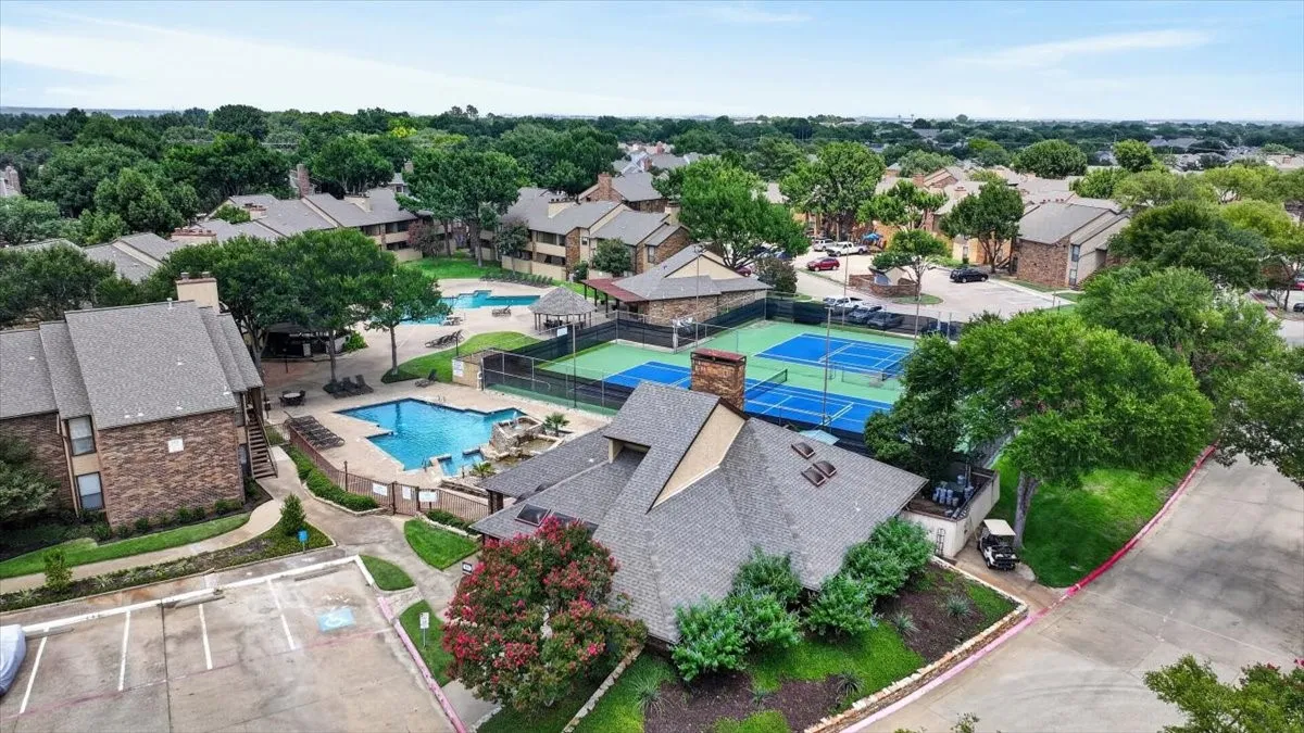 Expansive residential complex featuring multiple buildings with gabled roofs, multiple outdoor pools, and two tennis courts