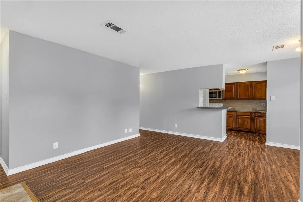 Fireplace with tile surround, wood-finish flooring, white walls, recessed ceiling lighting, and overhead lighting fixture.