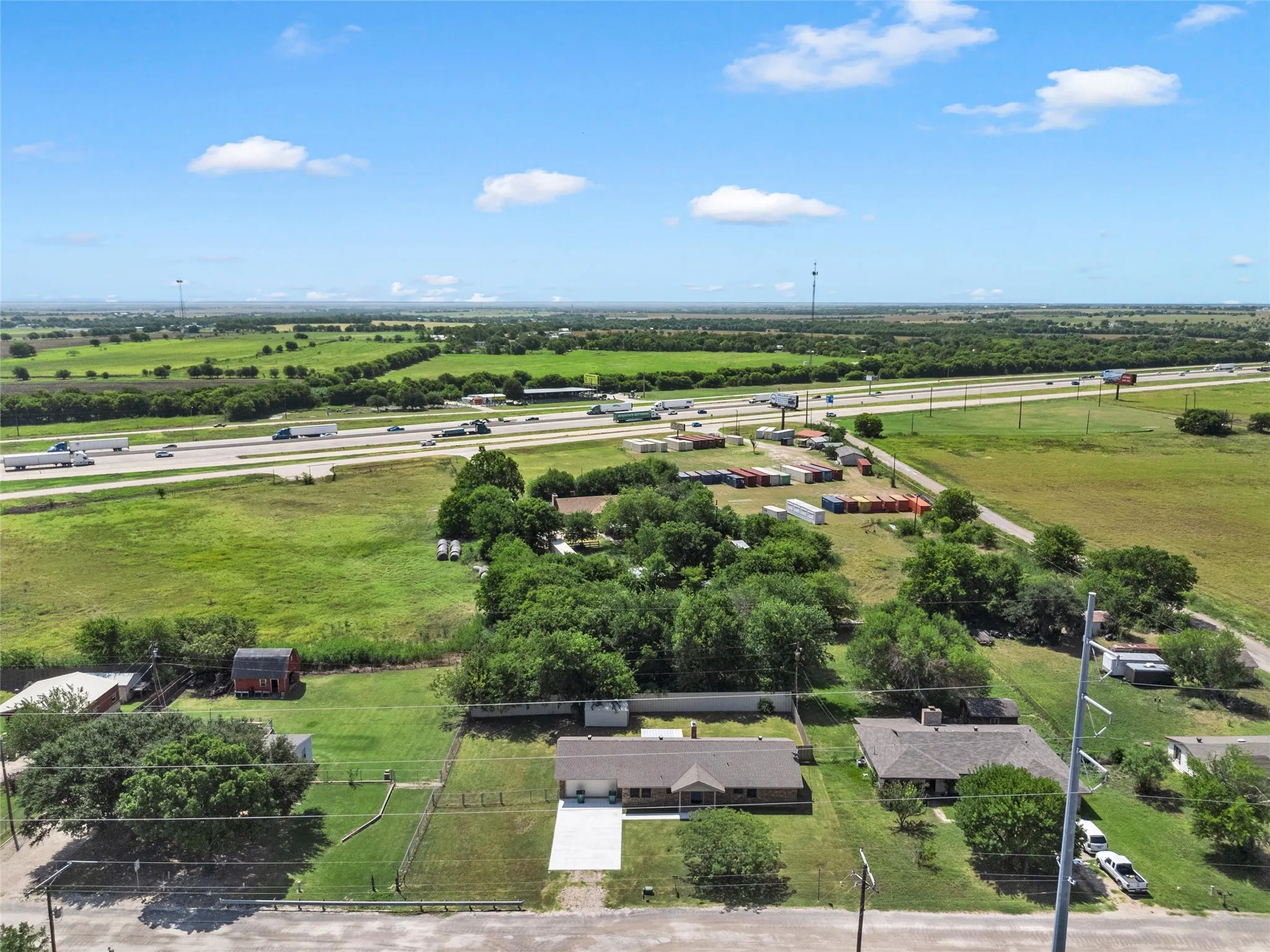 Expansive property featuring a single-story residence with an attached garage, a paved driveway, and established trees