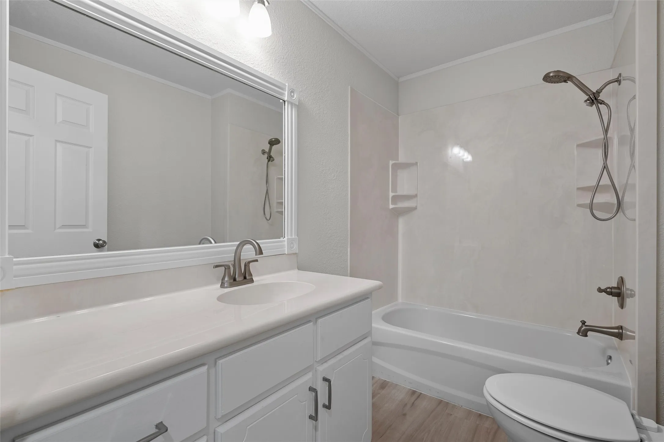 Bathroom featuring a single vanity with an integrated sink, brushed nickel faucet, and a large framed mirror