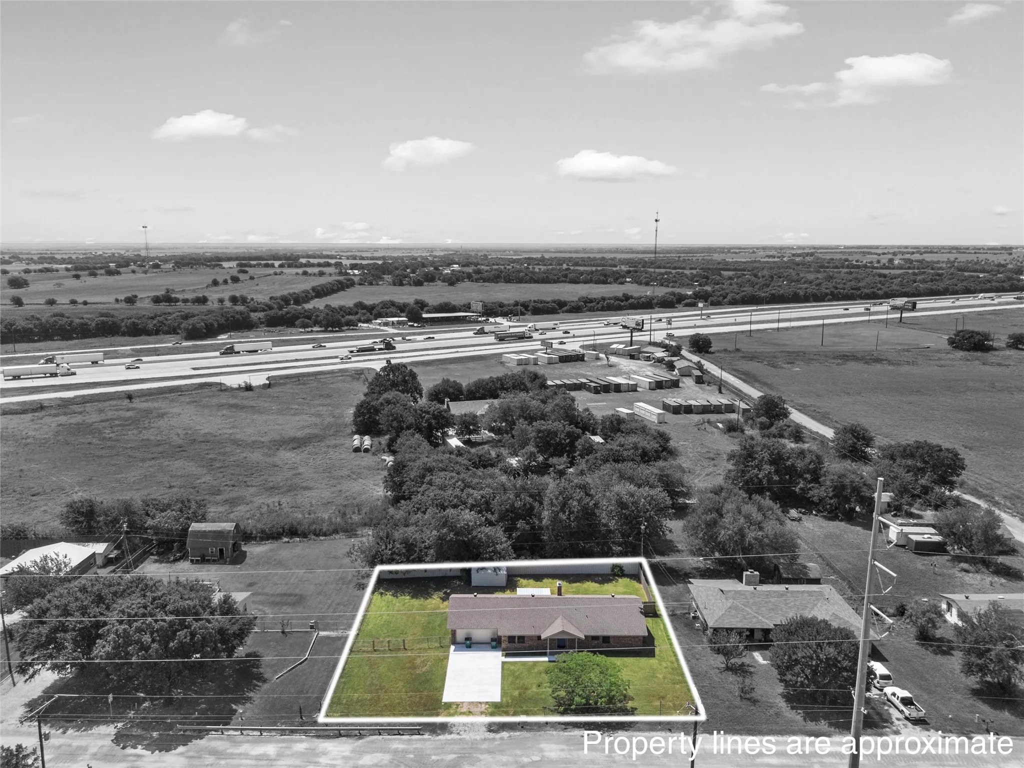 Aerial perspective highlighting a single-story residence with a brown shingle roof, a light-colored concrete driveway, and a partially fenced yard