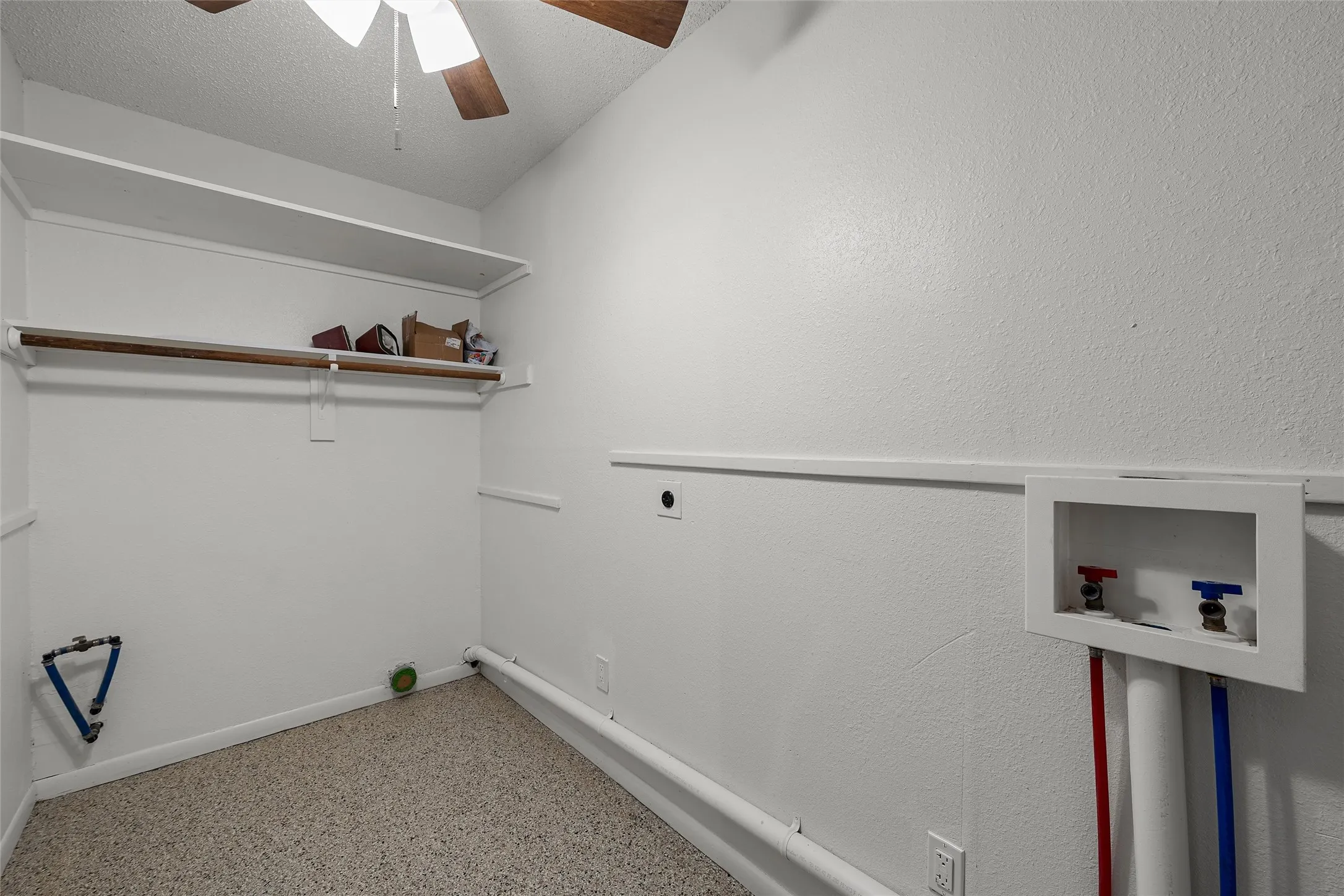Utility room featuring a ceiling fan, wall shelving, clothes hanging rod, and washer hookups