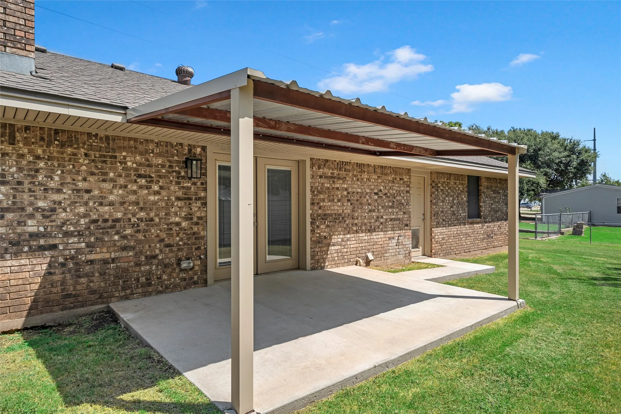 Covered concrete patio with direct access to interior via double glass doors
