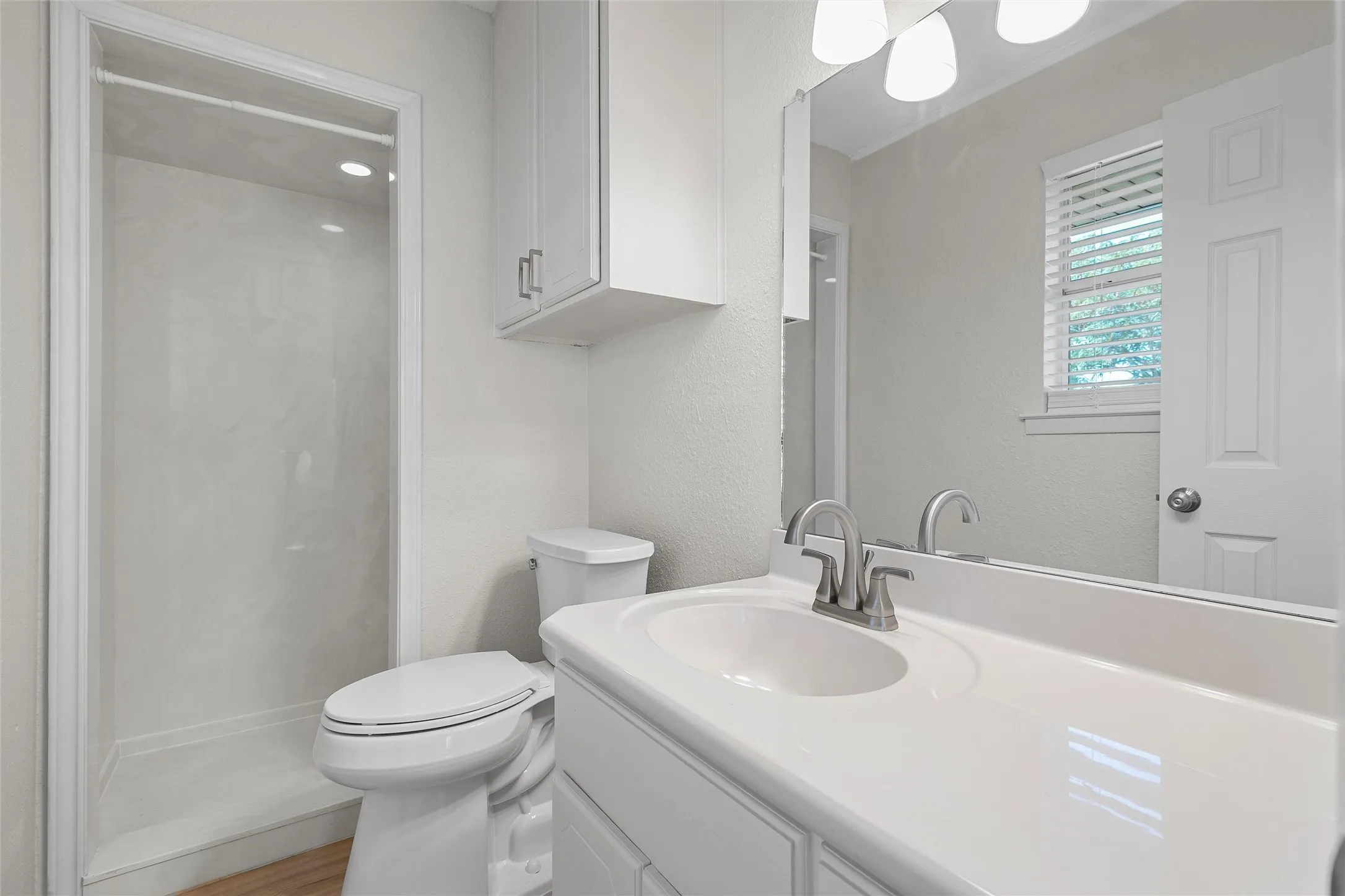 Bathroom featuring a white vanity with an integrated sink, brushed nickel faucet, and a large mirror