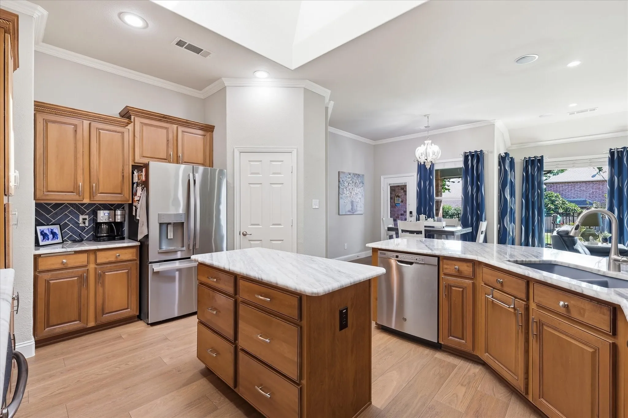 Kitchen featuring wood-finish cabinetry, stainless steel appliances, a center island with a stone-finish countertop, and a tile backsplash