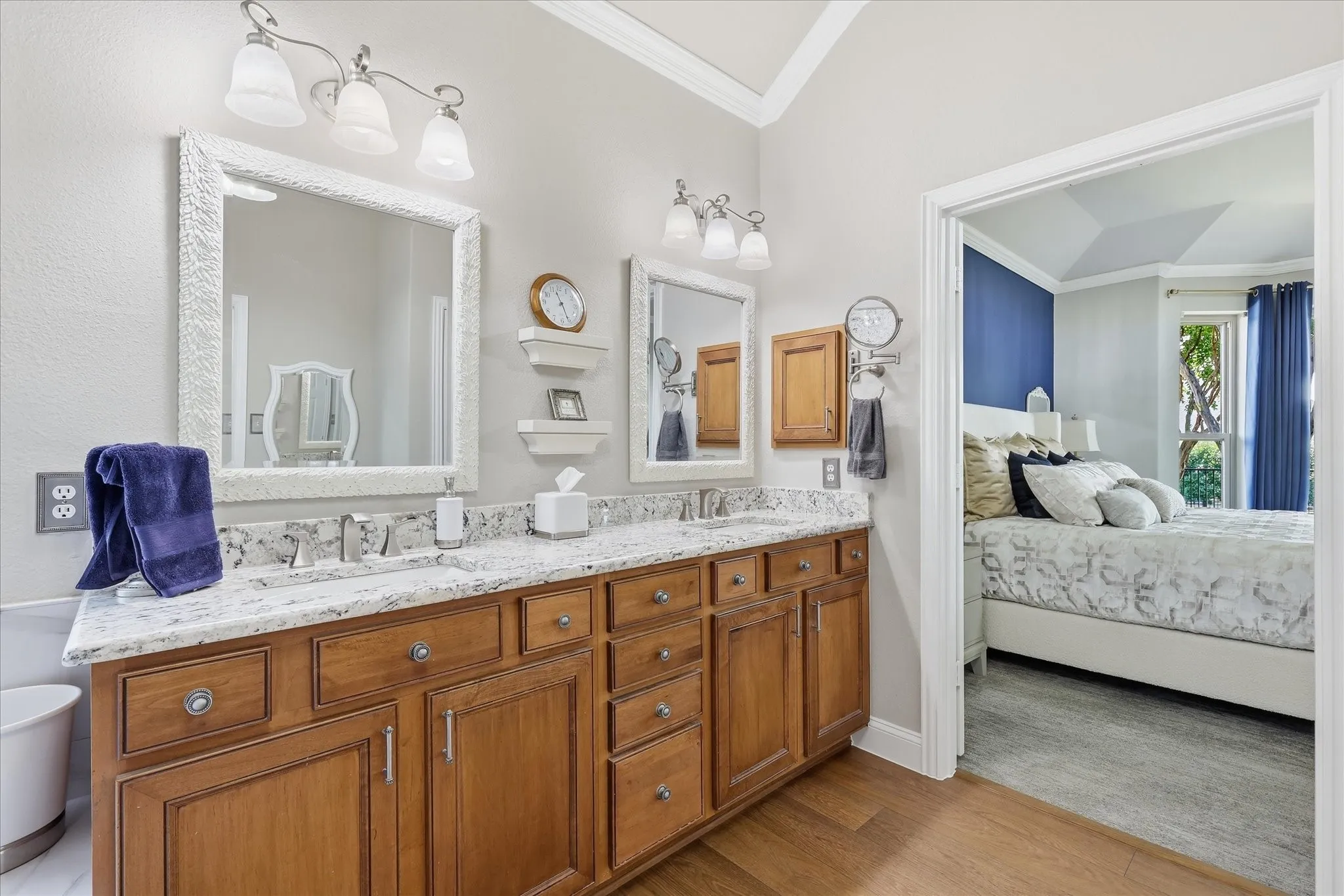 Dual vanity with wood cabinetry, granite countertop, and framed mirrors