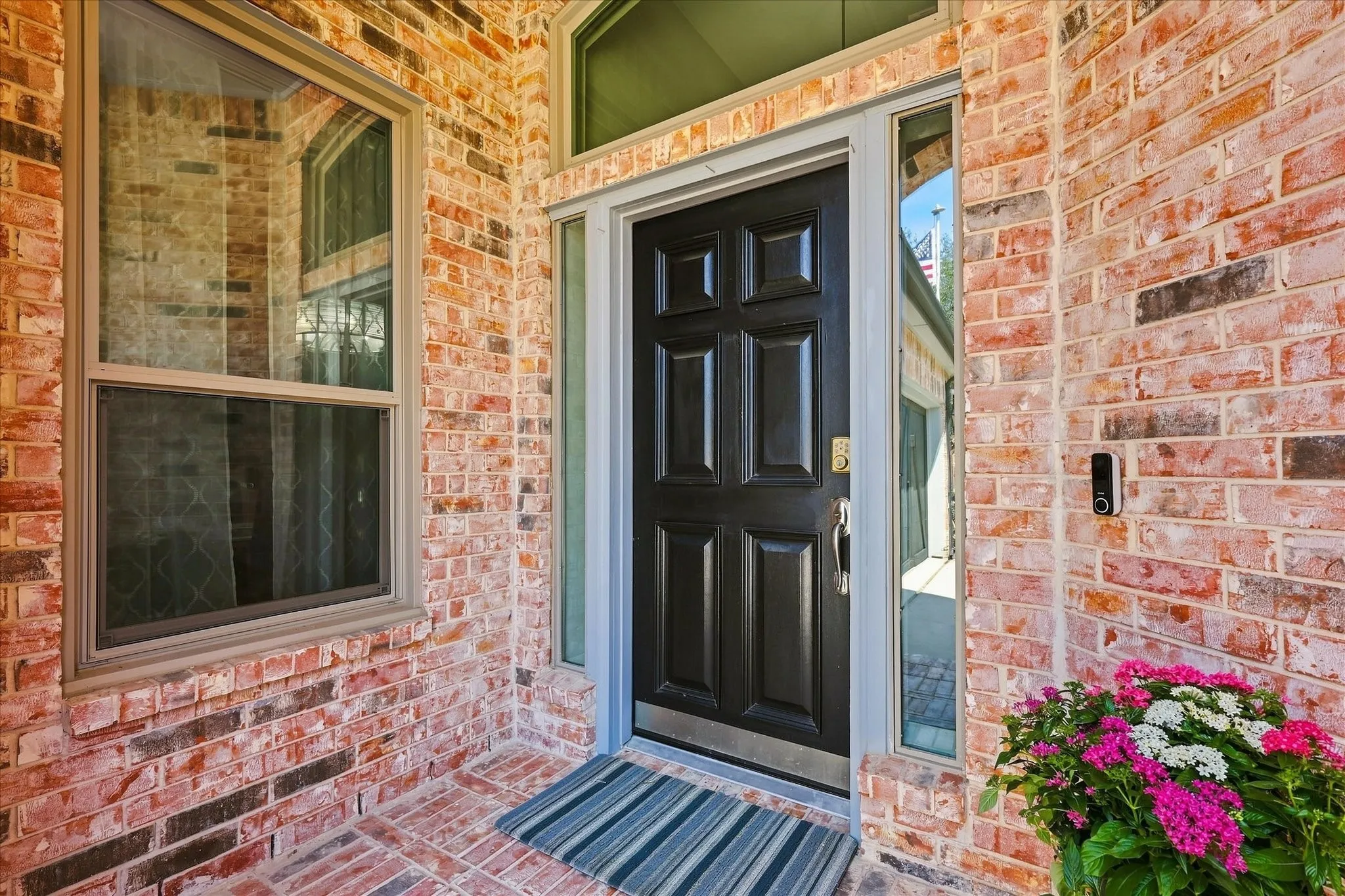 Brick exterior with a paneled front door, transom window, and clear glass sidelights