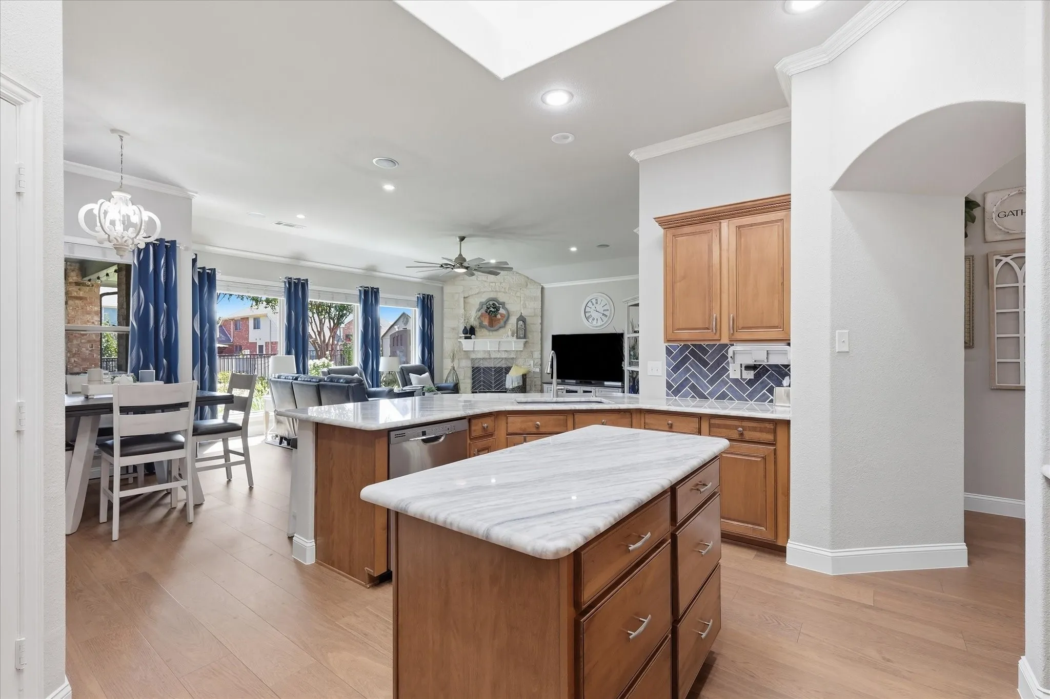 Kitchen featuring wood-finish flooring, central island with stone countertop, and wood cabinetry with subway tile backsplash
