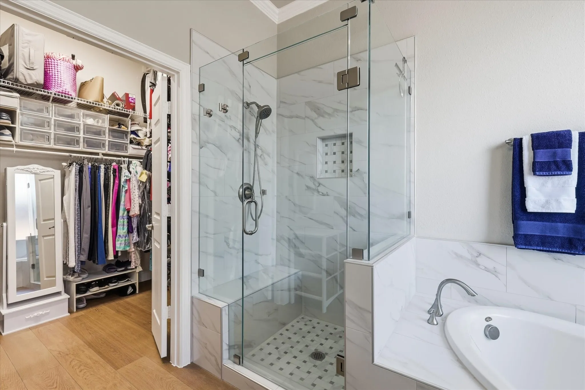 Glass-enclosed shower with a built-in bench, tiled shower niche, and white marble-look surround