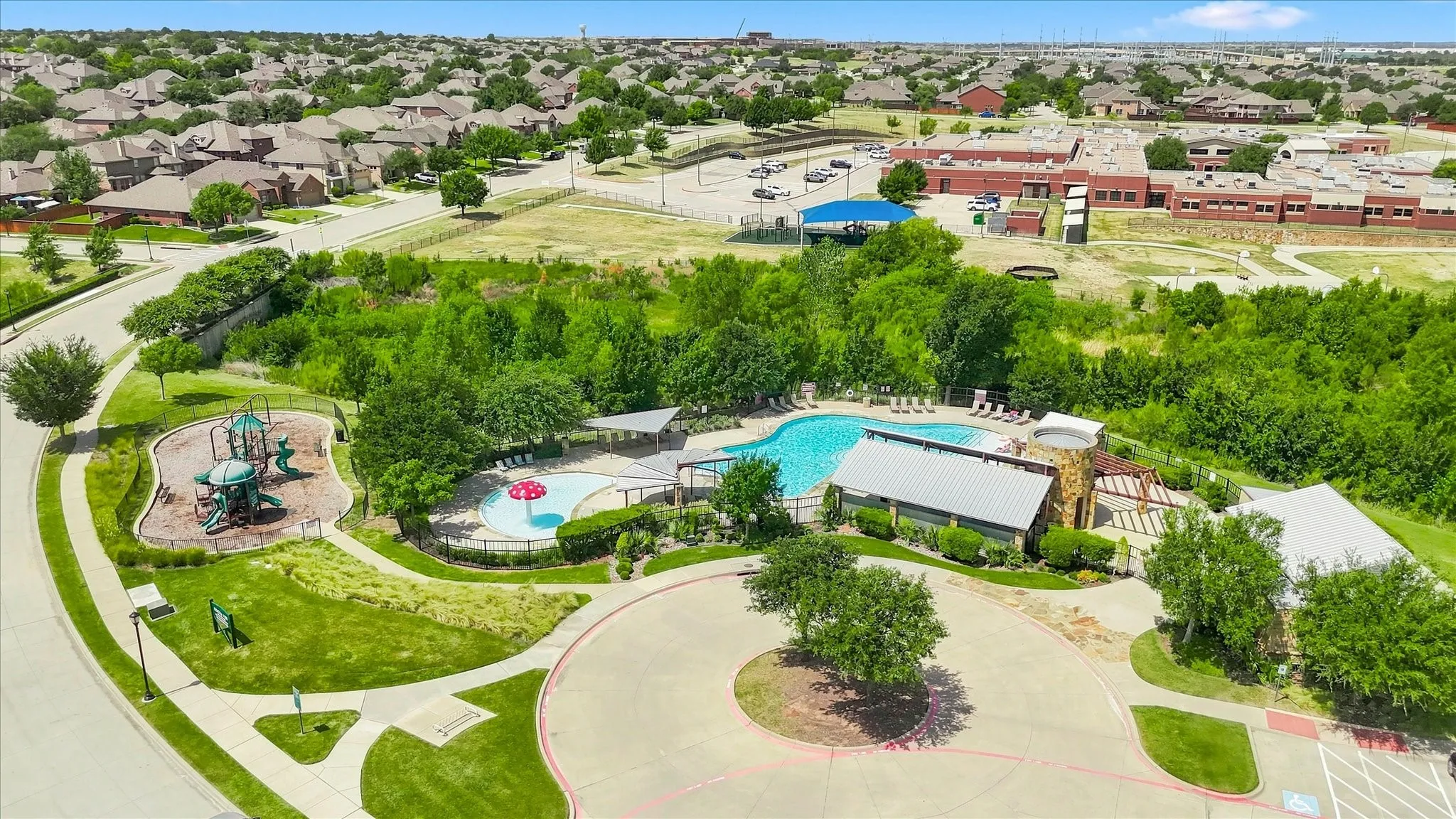 Community swimming pool with a dedicated splash pad, adjacent playground, and a stone-clad amenity building