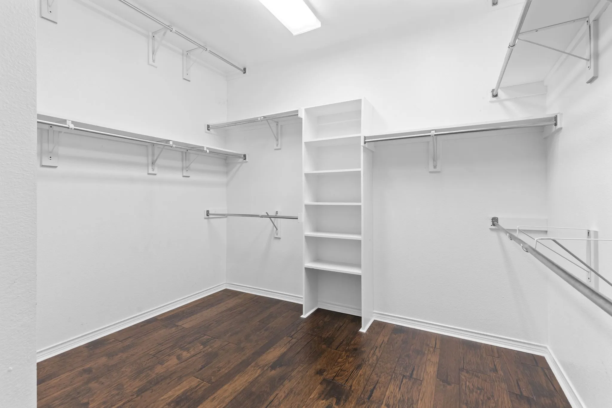 Walk-in closet Primary Bedroom featuring wood-finish flooring, built-in shelving, and multiple hanging rods
