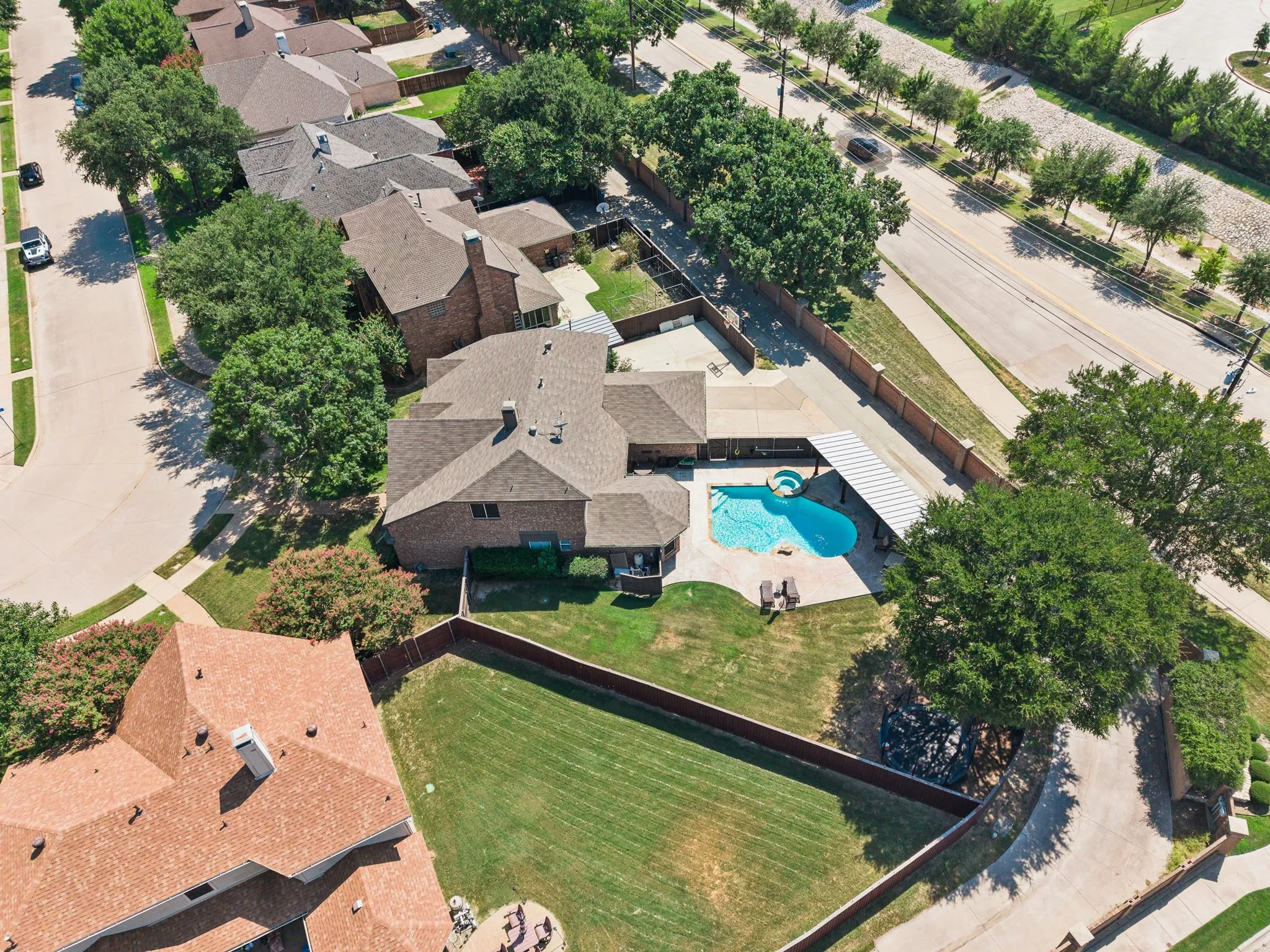 Brick exterior residence with a private swimming pool, covered patio, and fenced backyard