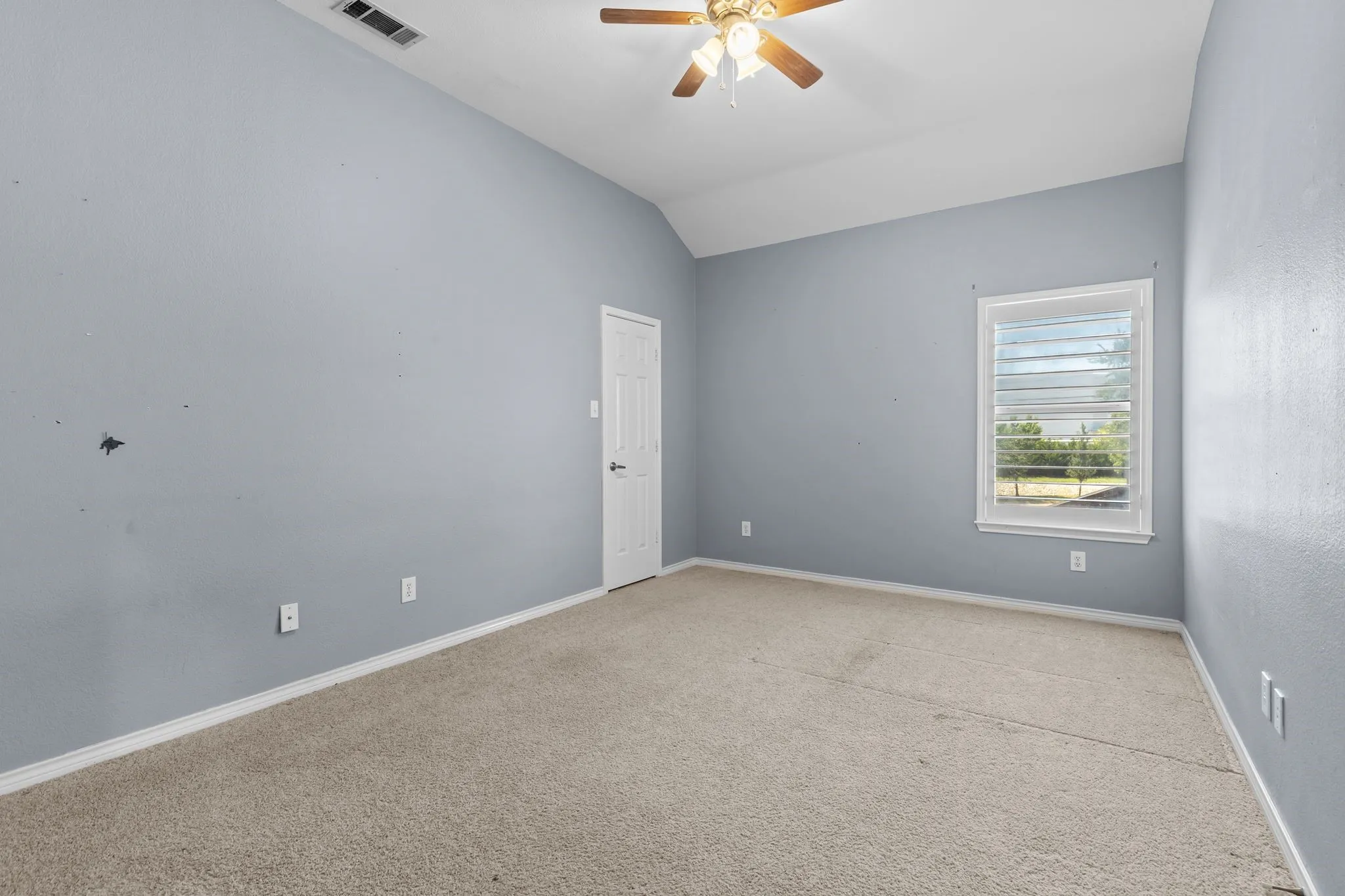 Vaulted ceiling with a ceiling fan, light-colored carpet, white trim, and a window with horizontal blinds