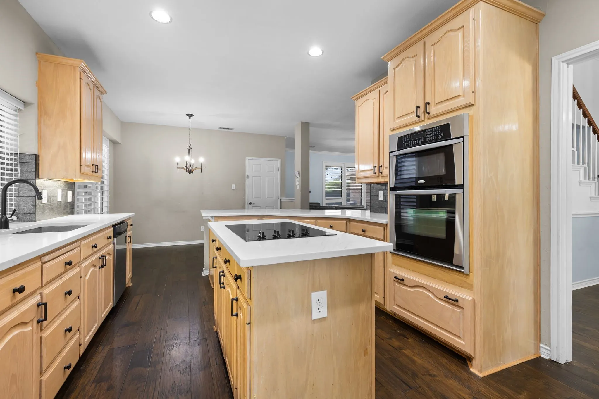 Kitchen featuring wood-finish flooring, light wood cabinetry with dark hardware, a built-in double oven, and white countertops