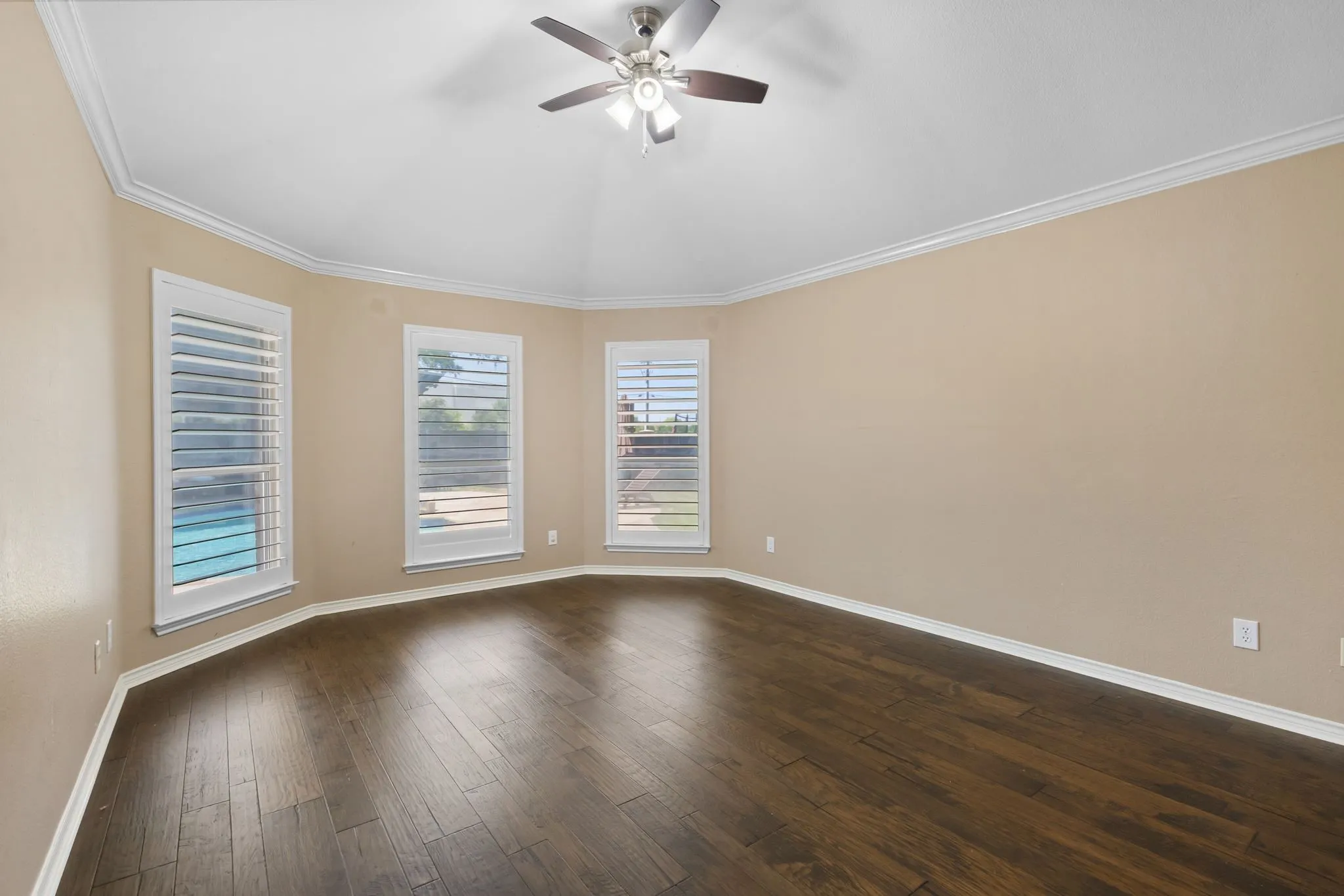 Vaulted ceiling with crown molding, wood-finish flooring, plantation shutters, and a ceiling fan with integrated lighting