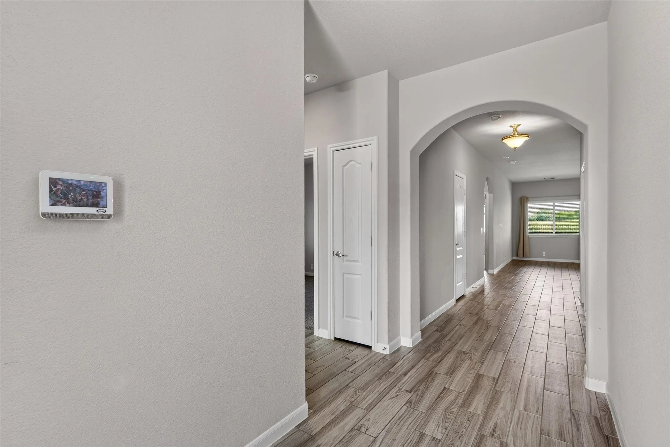 Entry hallway featuring wood-finish flooring, light grey wall paint, and white baseboards