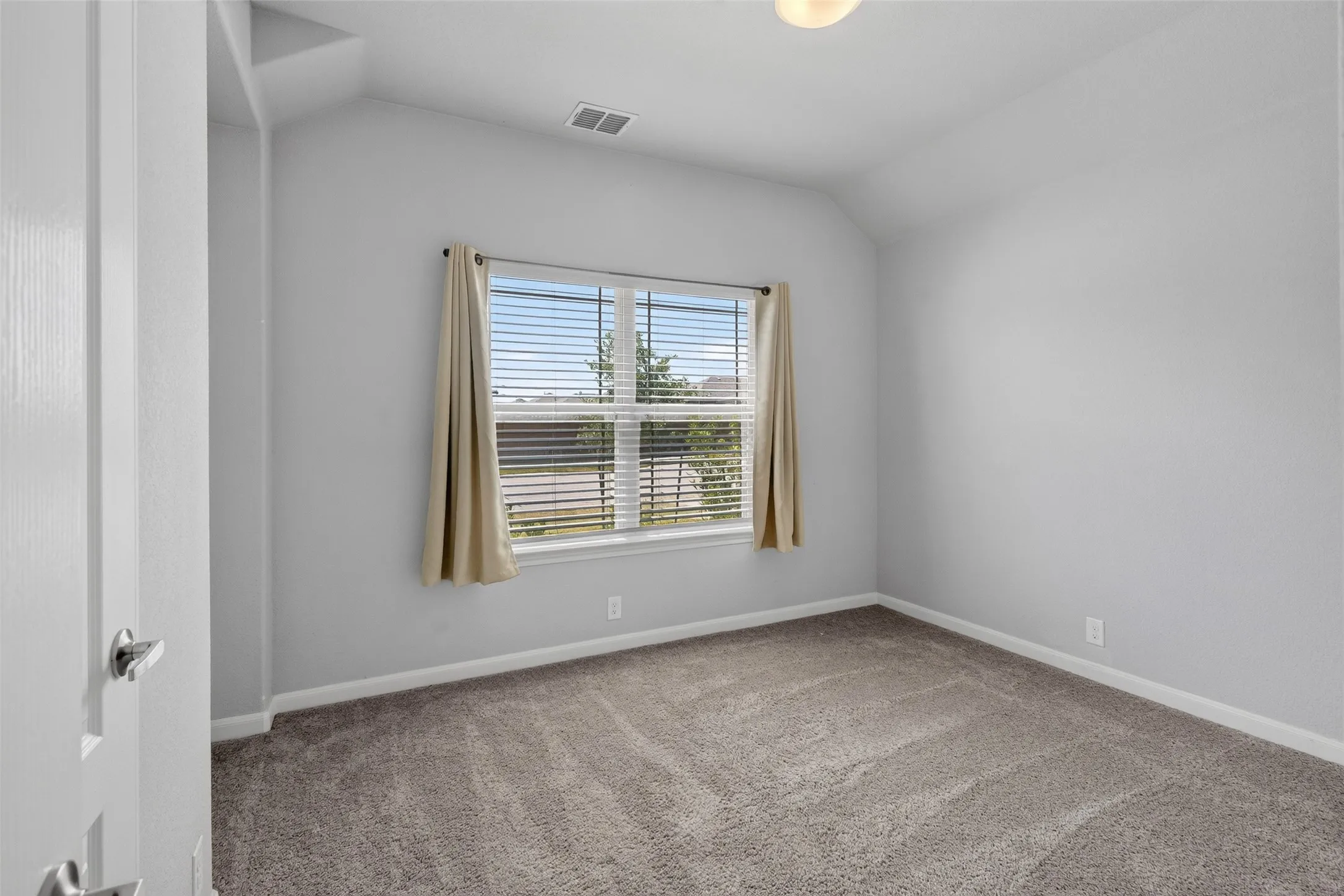 Carpeted interior with light gray walls, a single window with blinds, and white trim molding