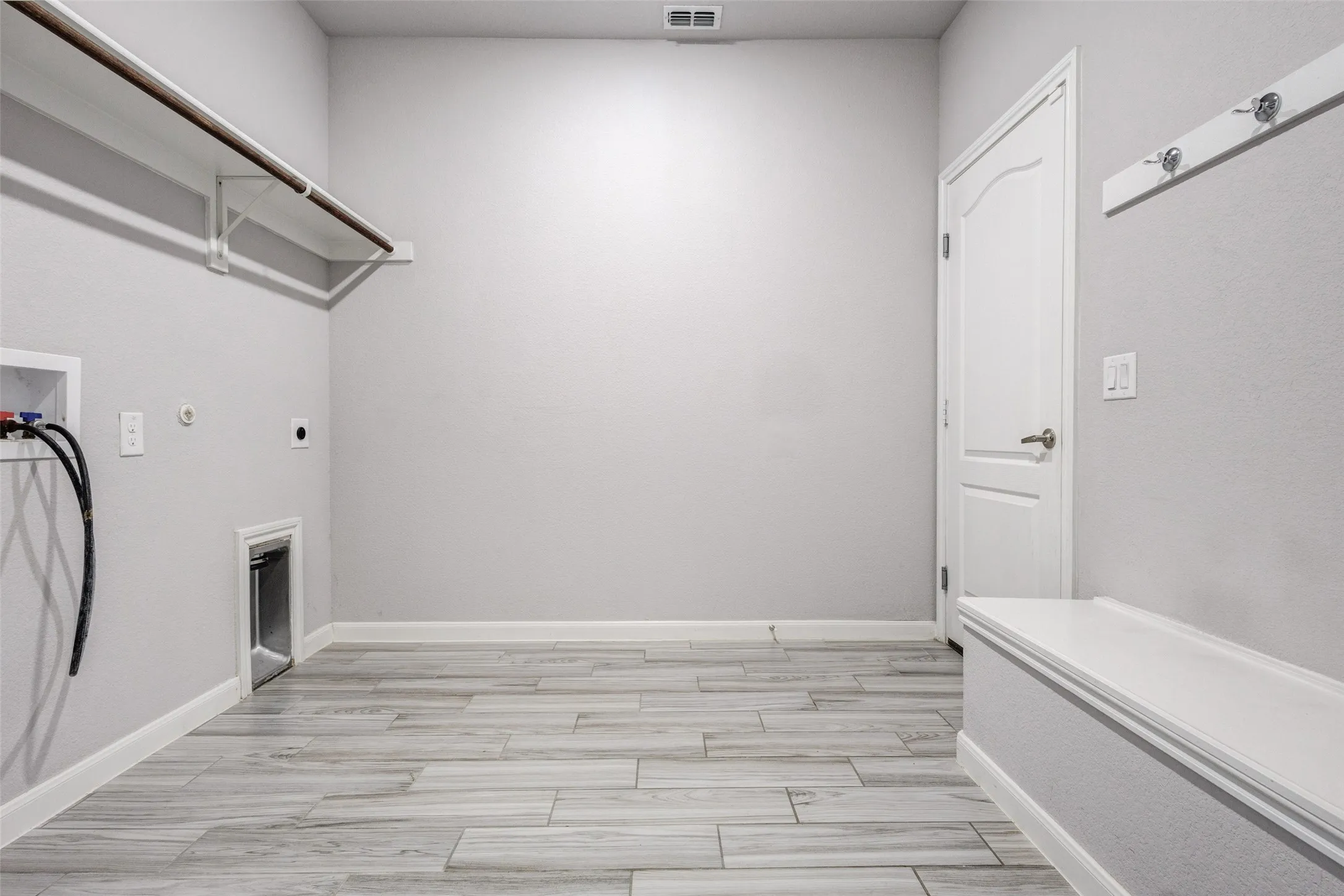 Oversized Laundry area featuring wood-finish tile flooring, a built-in storage bench, and a mounted clothing rack