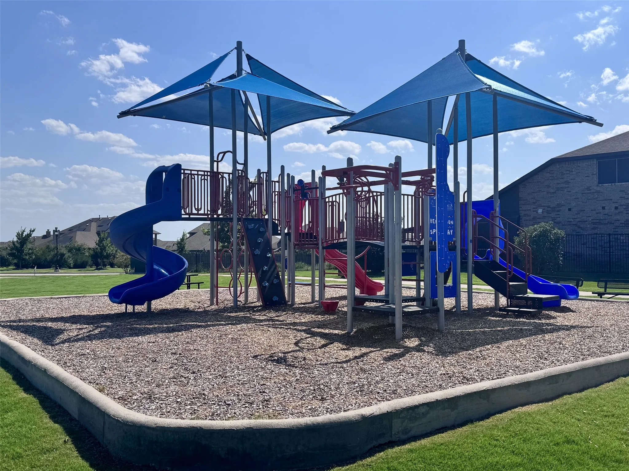 Community playground featuring multiple slides, climbing structures, and shade canopies