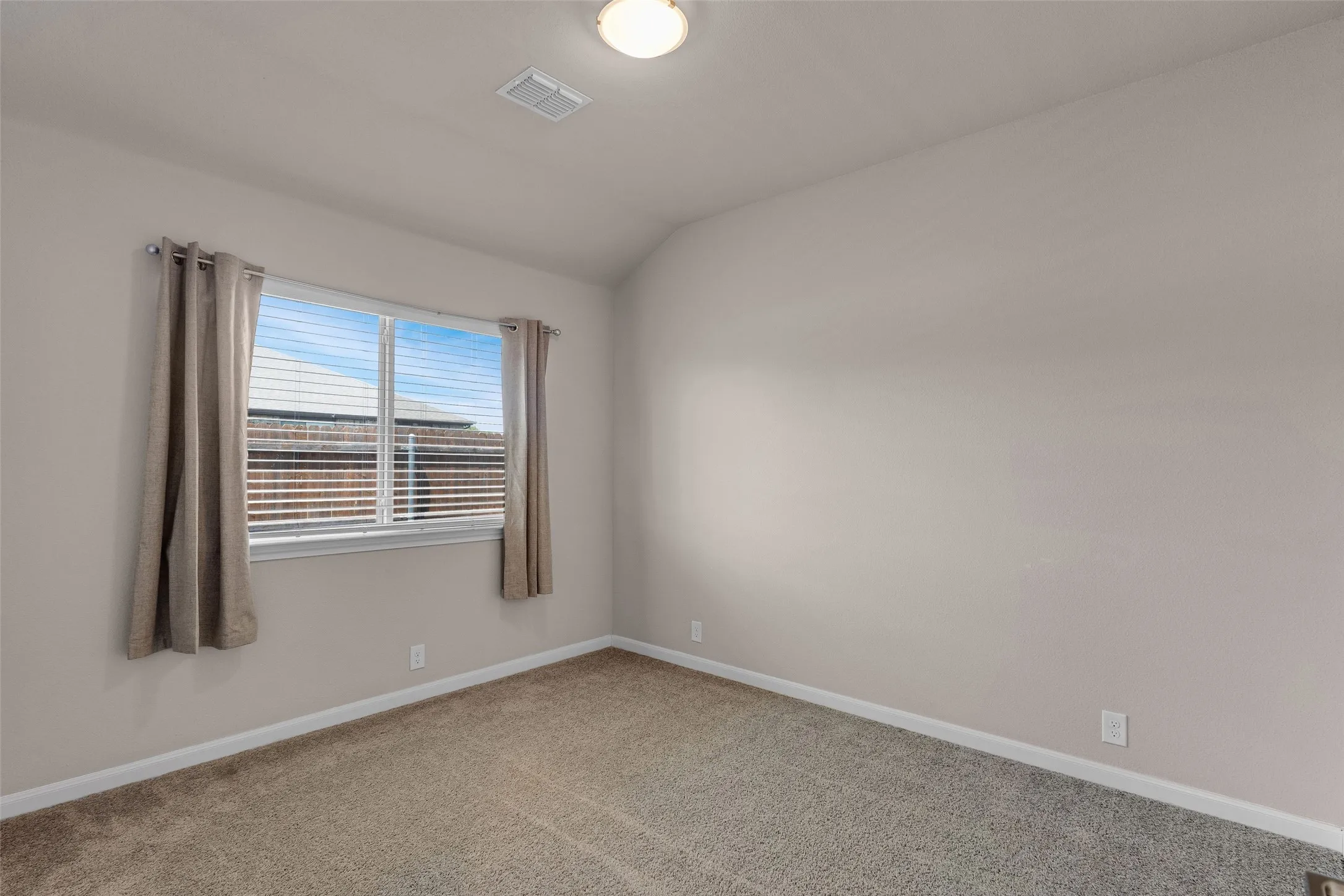 Carpeted room featuring a double window with blinds, light gray walls, white baseboards, and a flush mount ceiling light