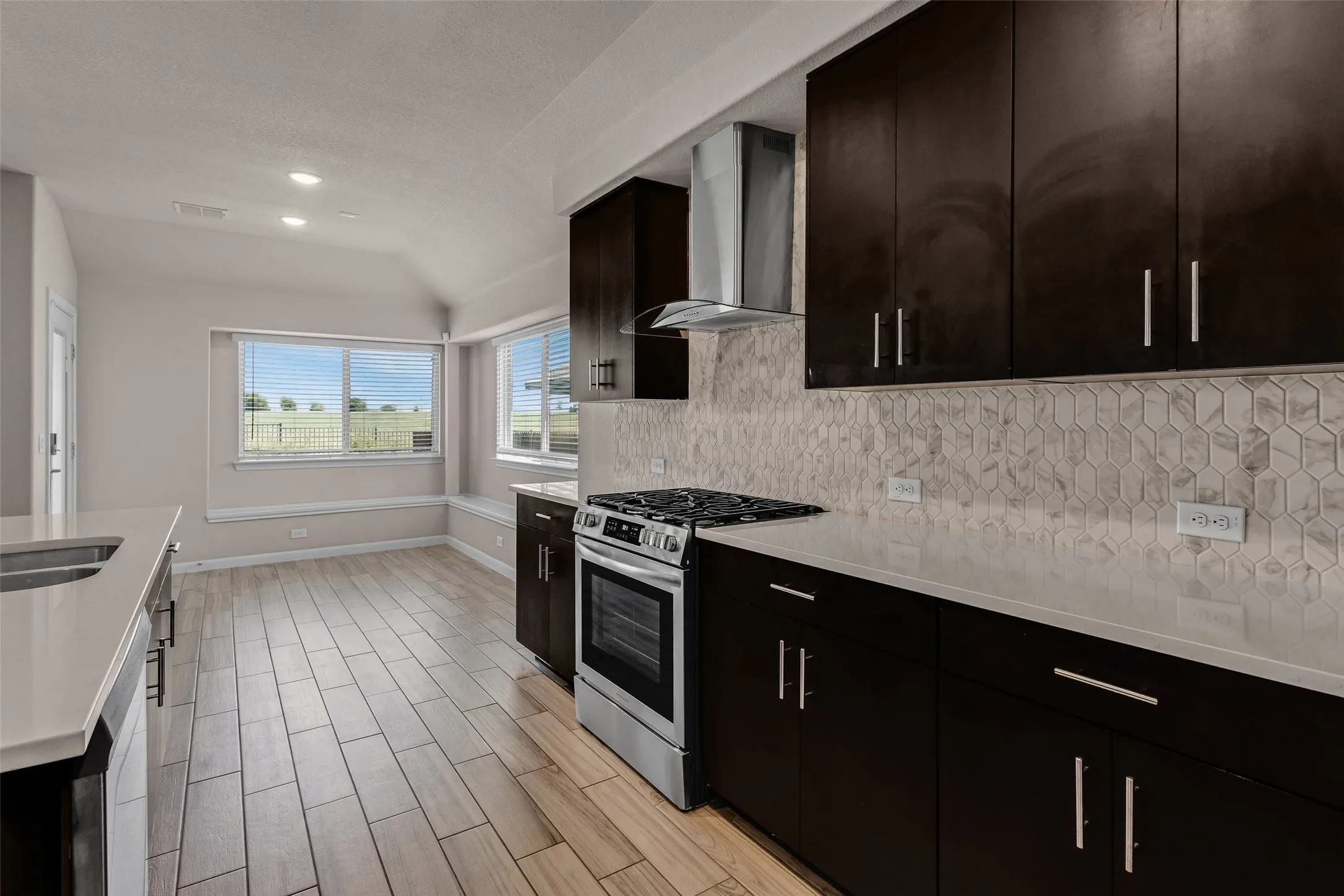 Contemporary kitchen featuring dark wood cabinetry, light countertops, and a white geometric tile backsplash