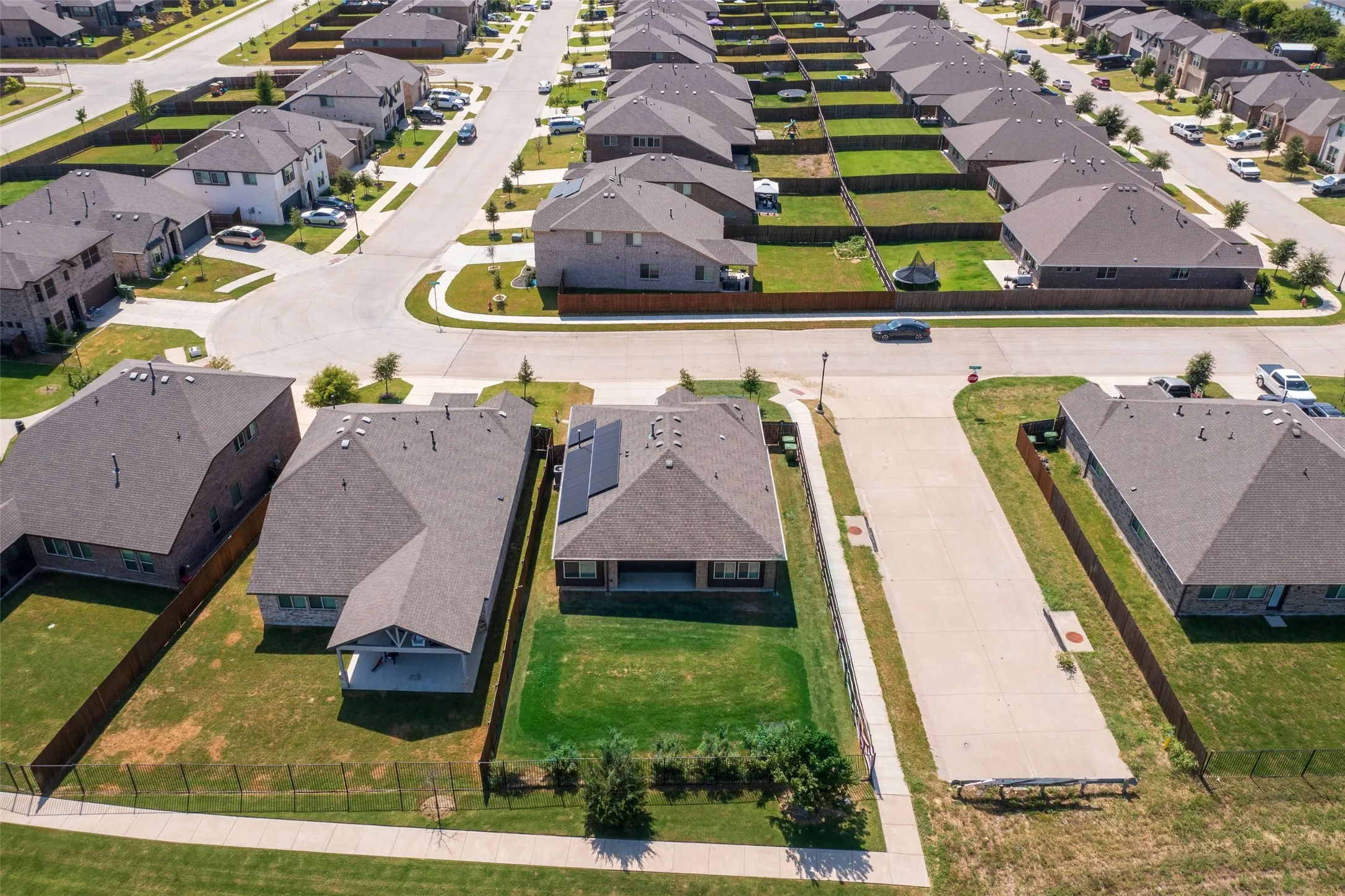Aerial perspective showcasing a residential neighborhood with uniformly designed homes featuring dark gray shingle roofs