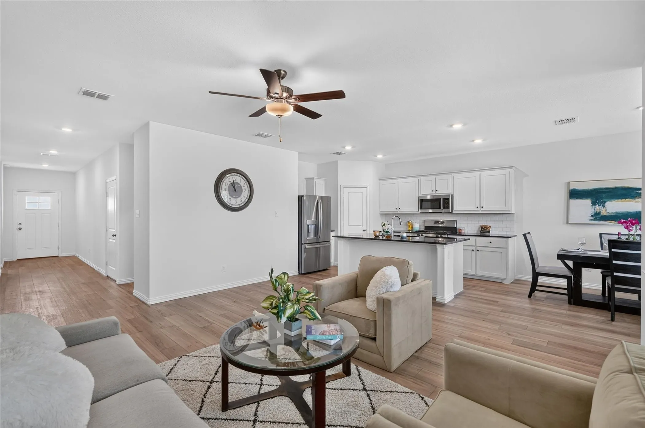 Open-concept living space featuring a ceiling fan with brushed metal finish, recessed lighting throughout, and wood-finish flooring