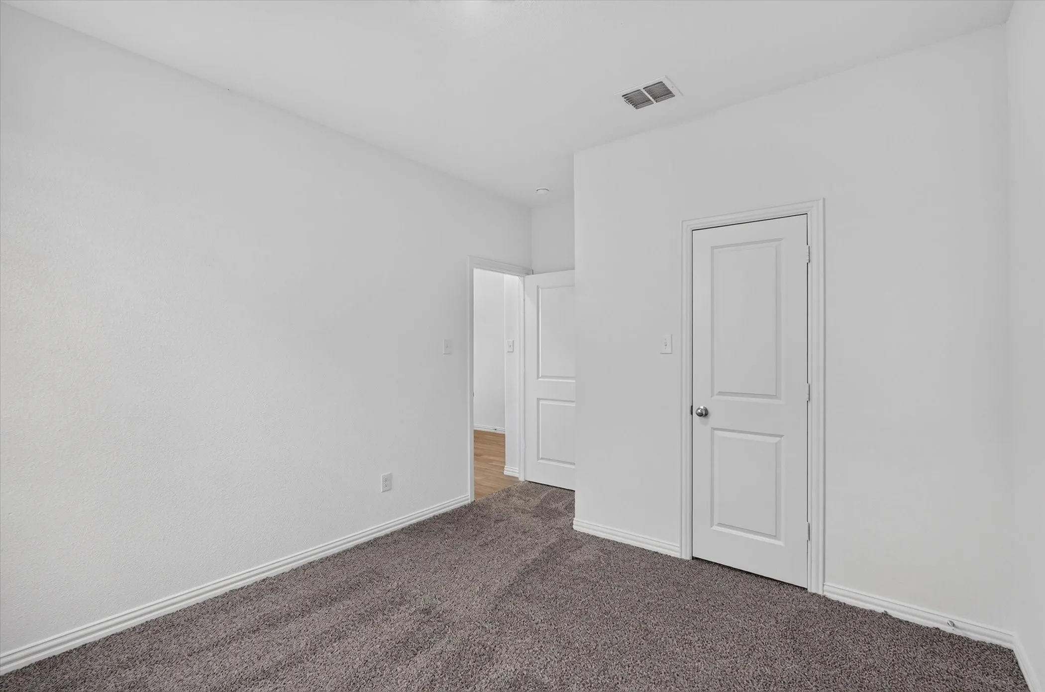 Bedroom with plush gray carpet, white painted walls, and white baseboards