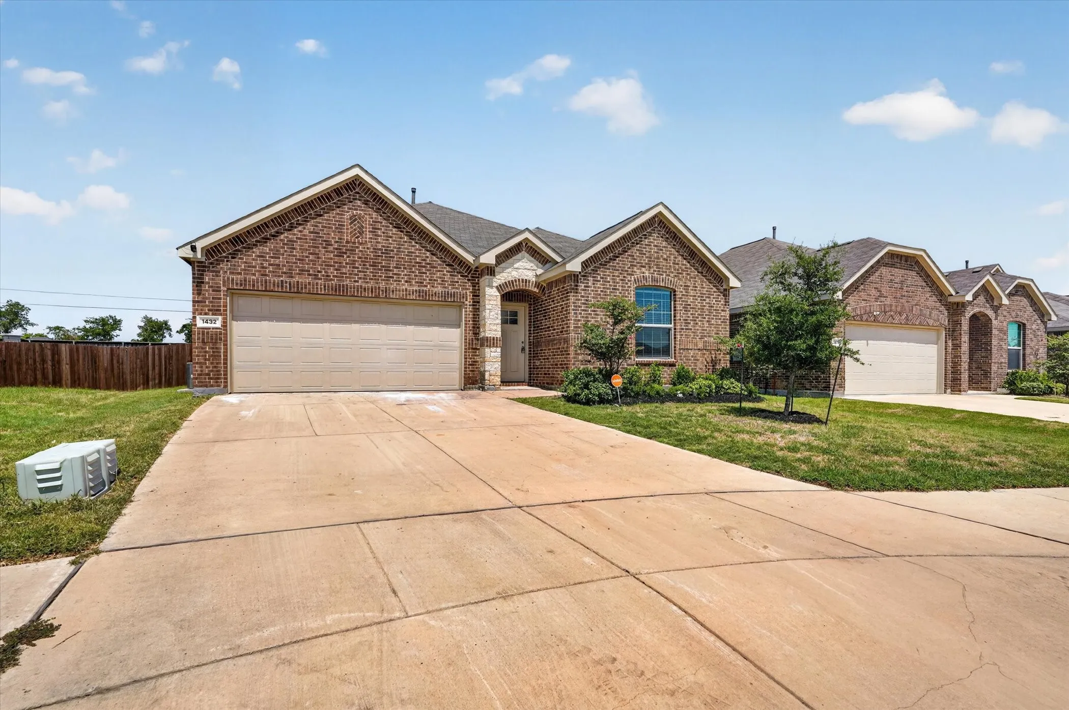 Welcoming brick exterior with a spacious two-car garage and expansive concrete driveway