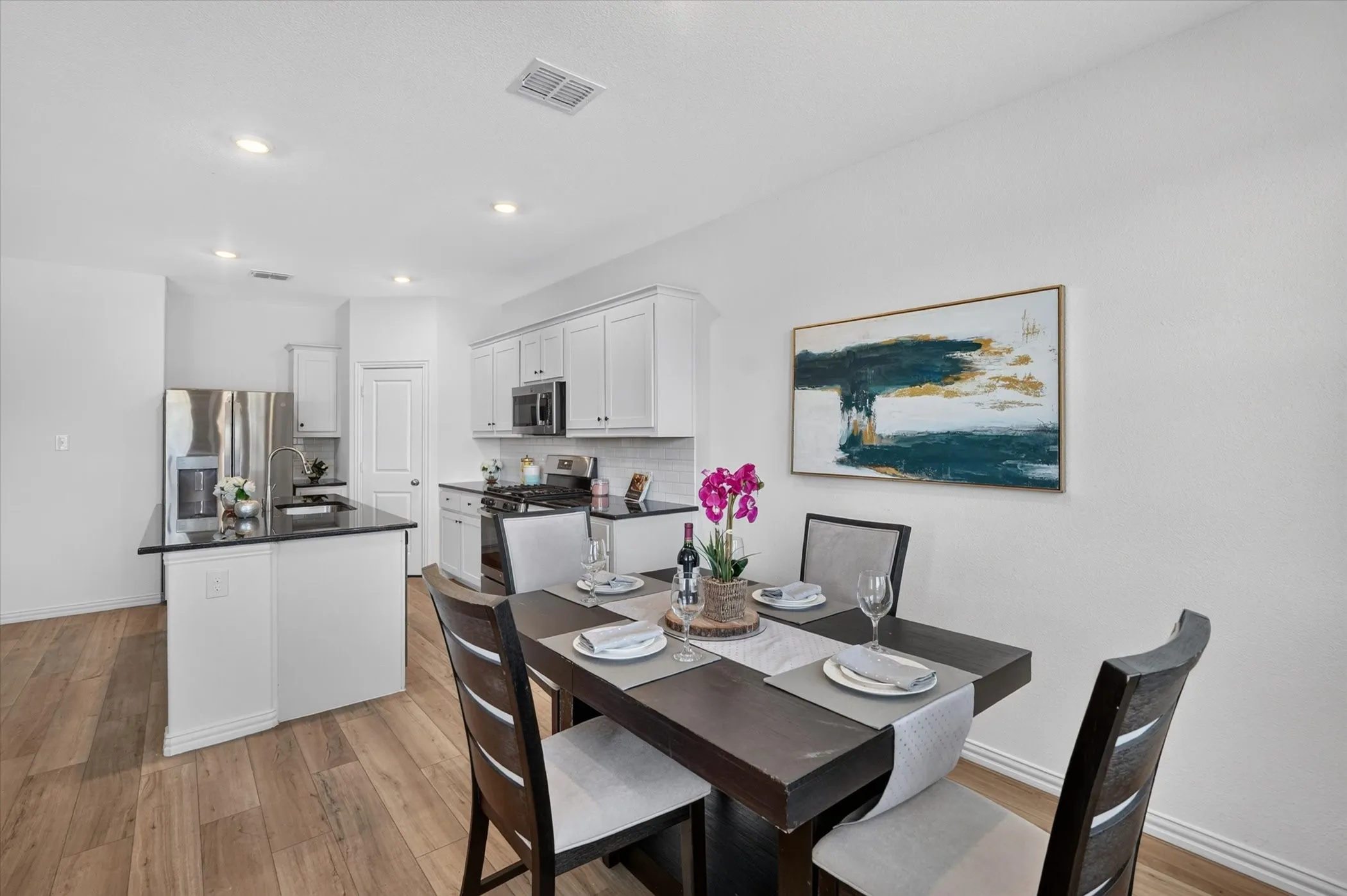 Open-concept living space featuring wood-finish flooring, recessed lighting, and a kitchen island with dark countertops