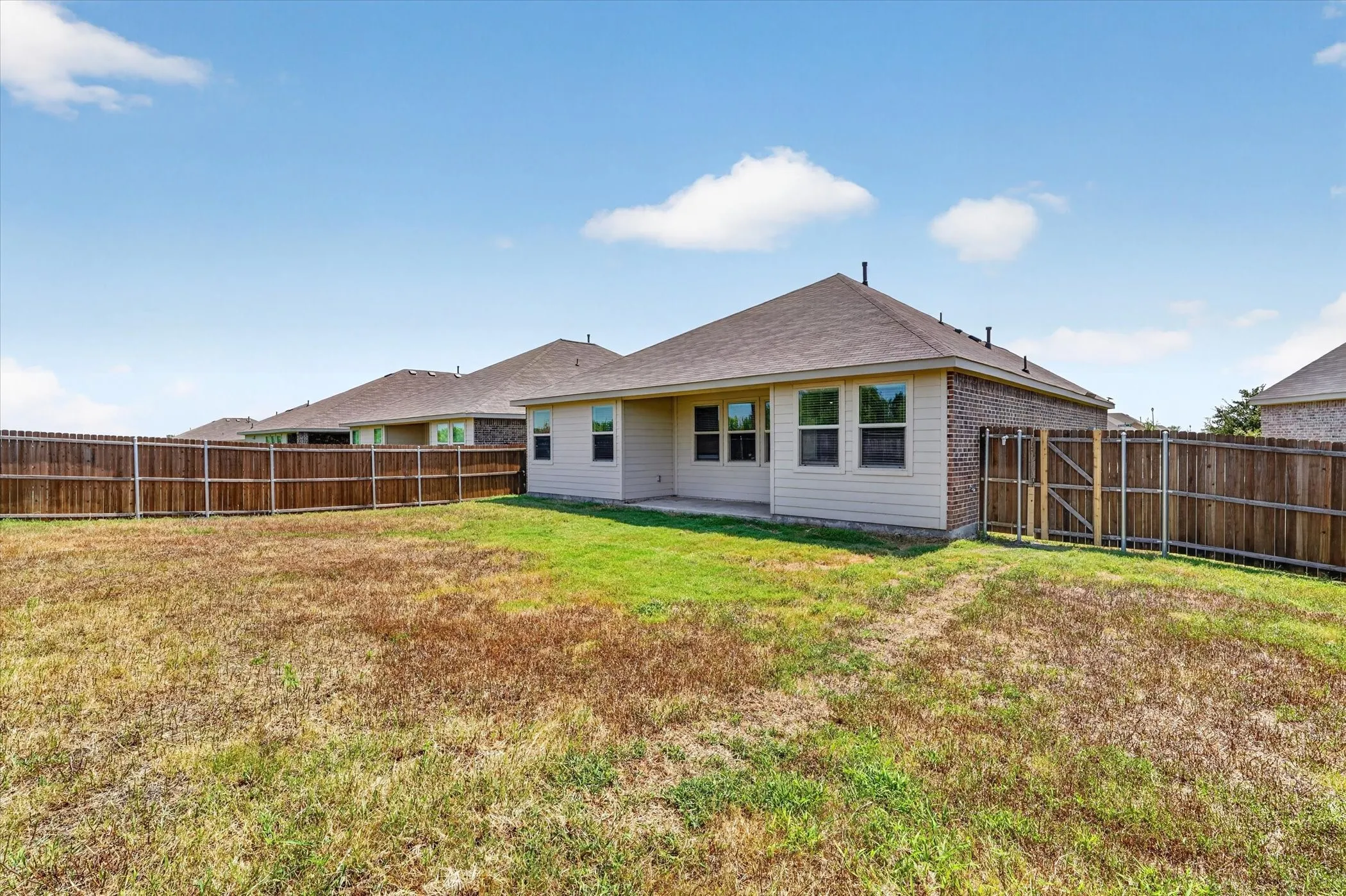 Spacious single-story home with a generous backyard featuring a manicured lawn and wooden privacy fencing