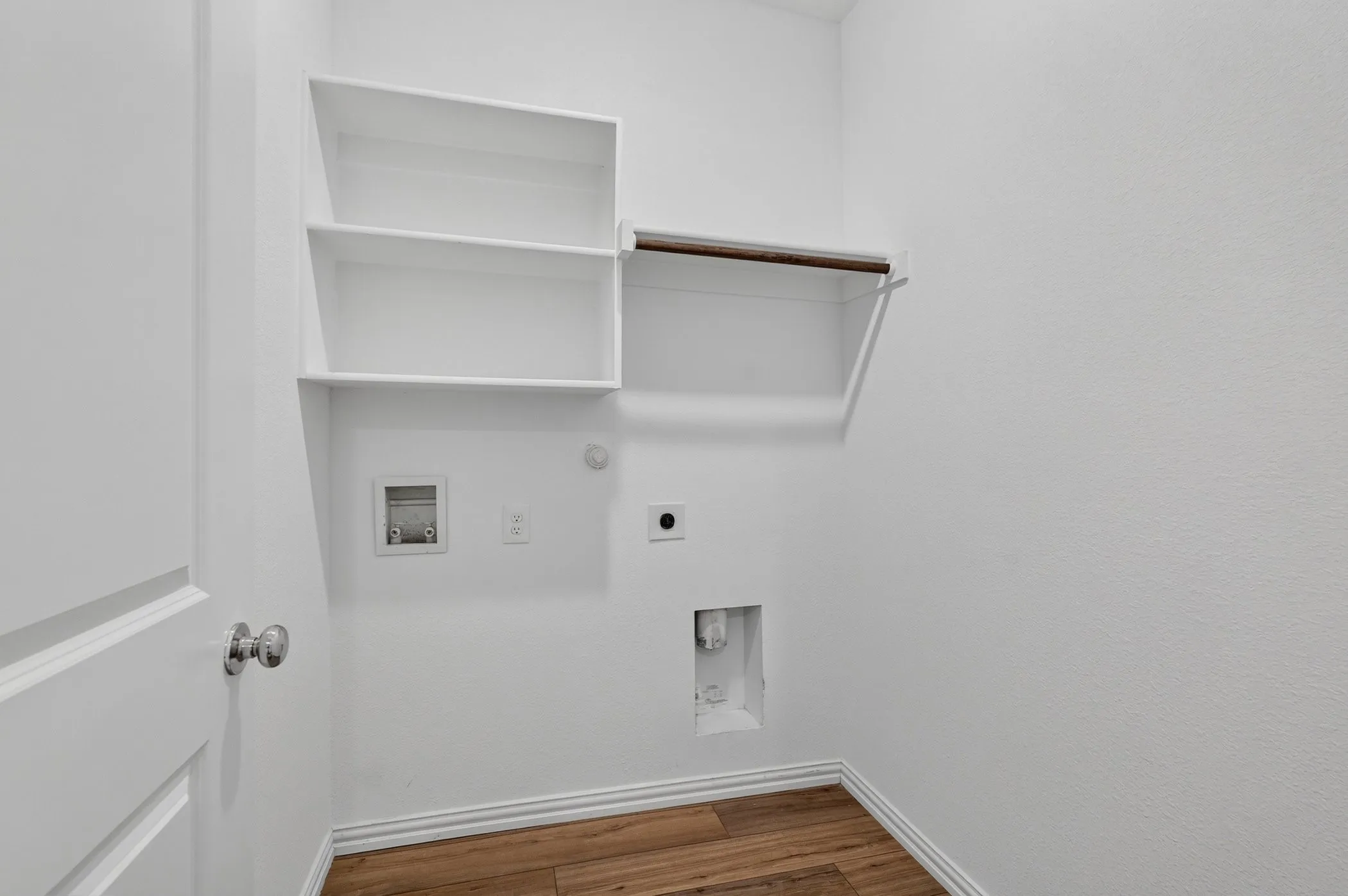 Utility area with white walls, wood-finish flooring, and white baseboards