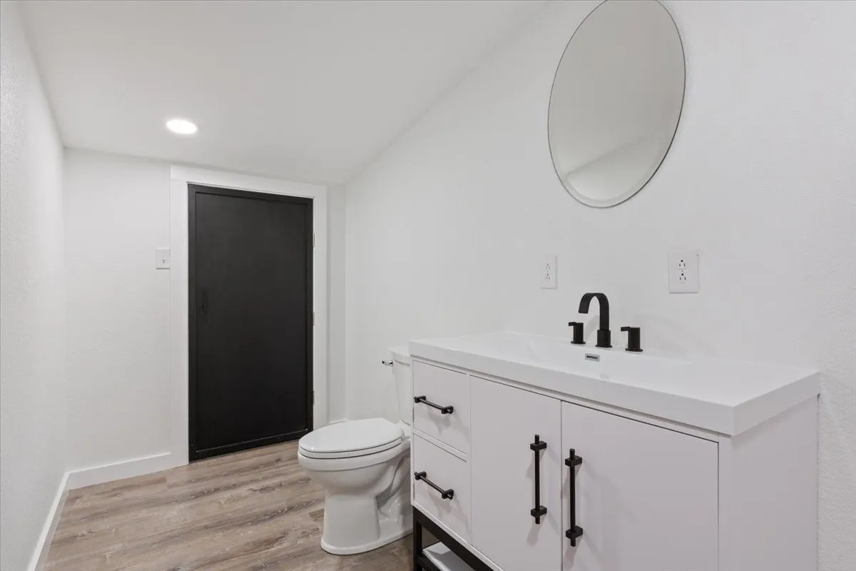 Second primary bathroom (upstairs) #1. Modern bathroom featuring a white vanity with matte black hardware, a circular mirror, and a contemporary black faucet