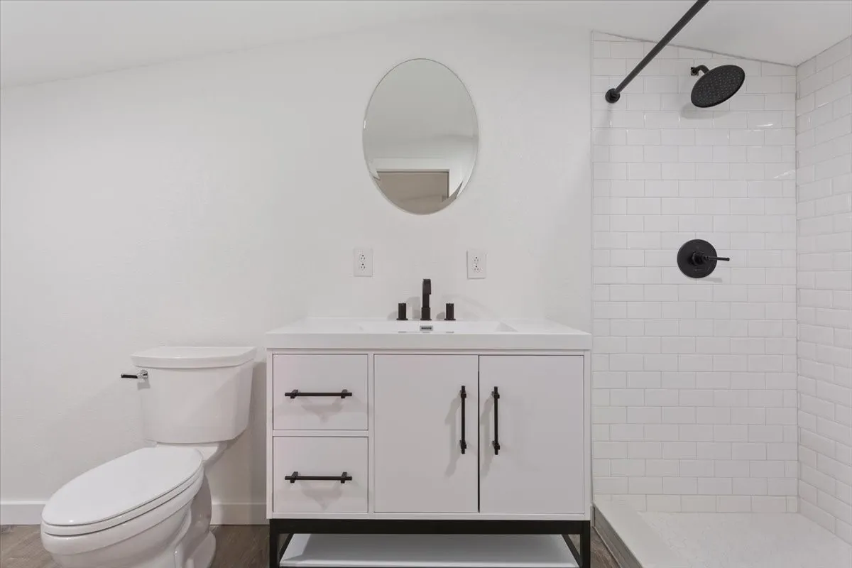 Second primary bathroom (upstairs) #2. Bathroom featuring a white vanity with matte black hardware, an oval mirror, and a tiled shower with matte black fixtures