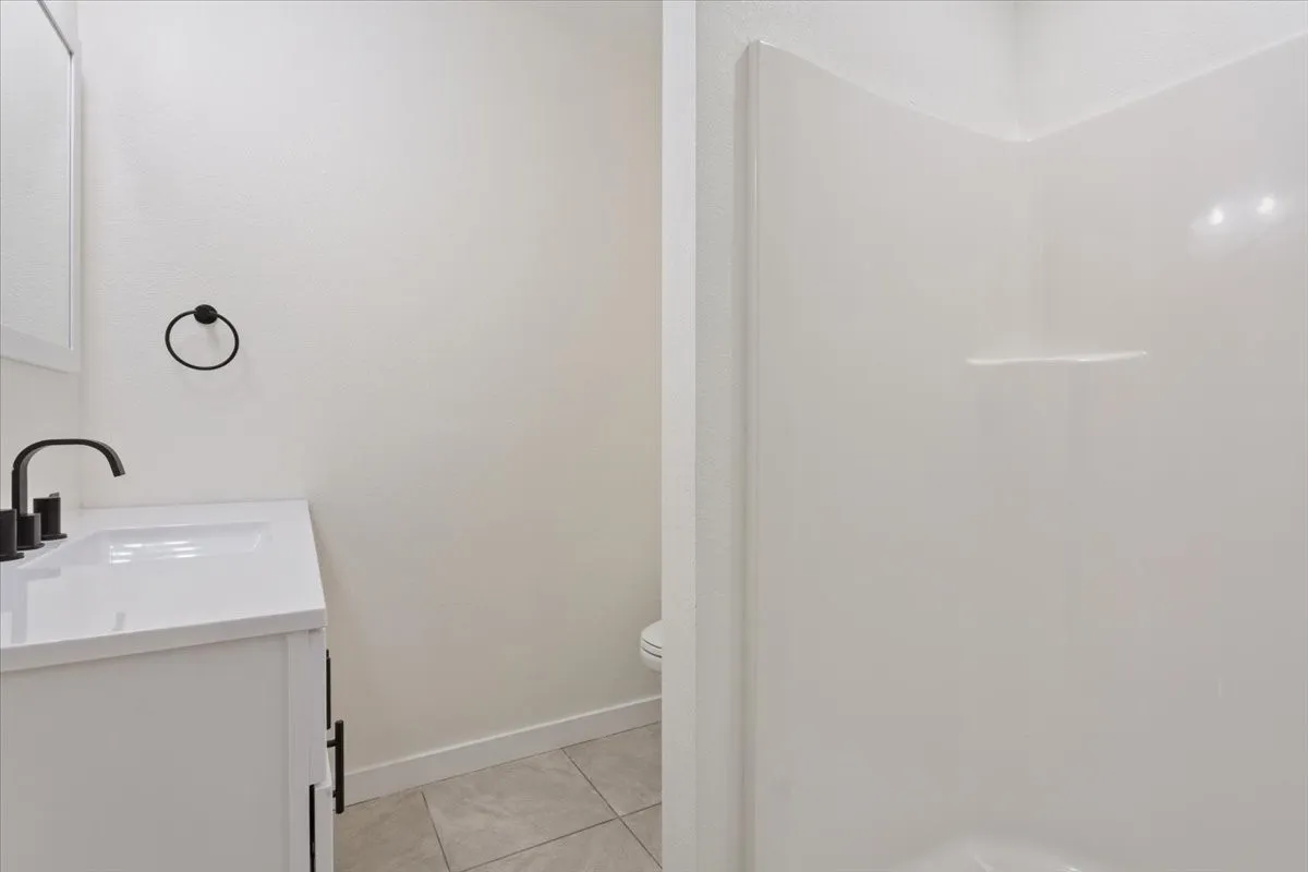 Downstairs bathroom #2, attached to kitchen. Bathroom featuring a white vanity with integrated sink, matte black faucet, and a contemporary towel ring