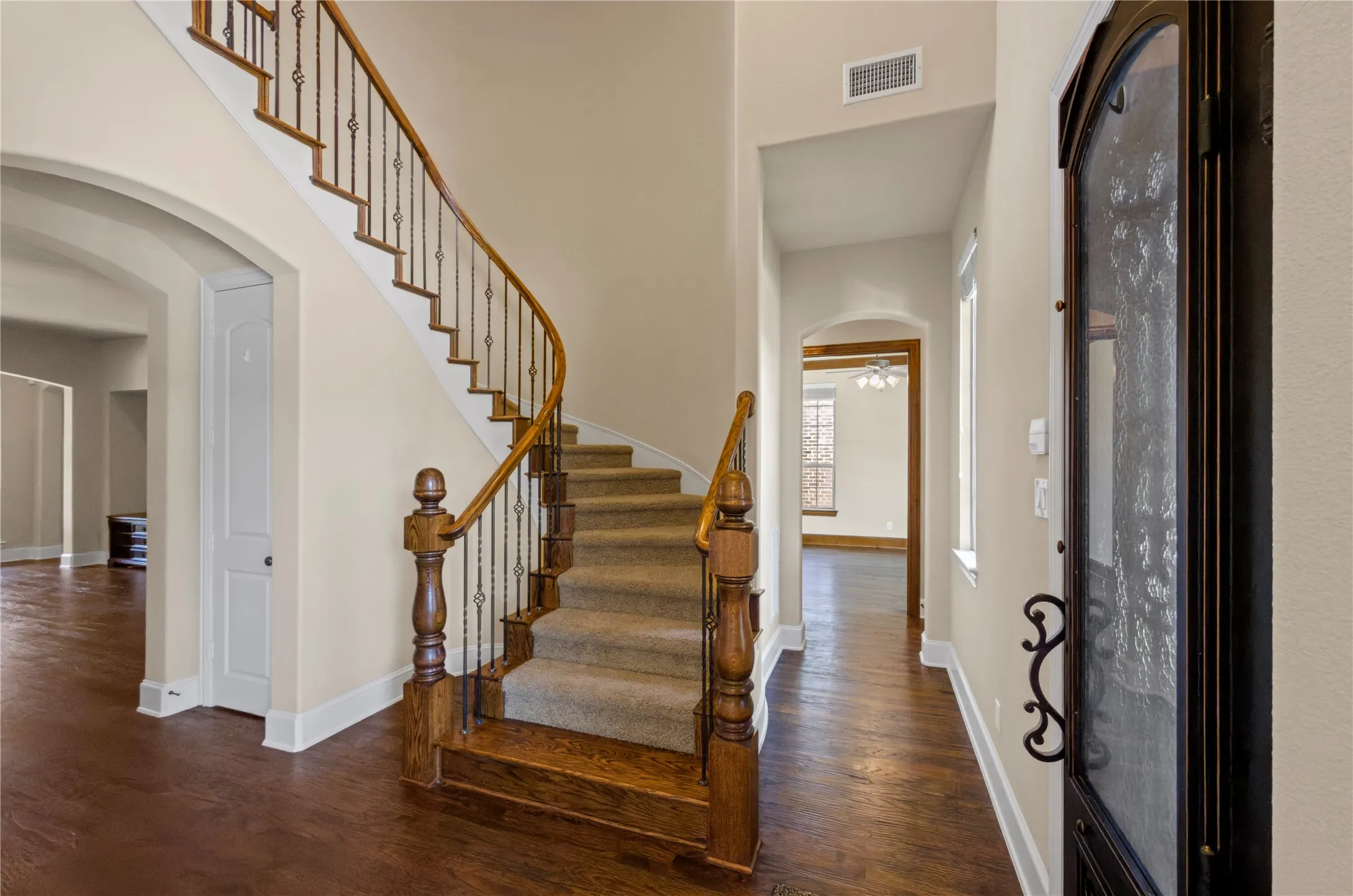 Grand entryway featuring a curved staircase with wrought iron balusters and wood-finish flooring
