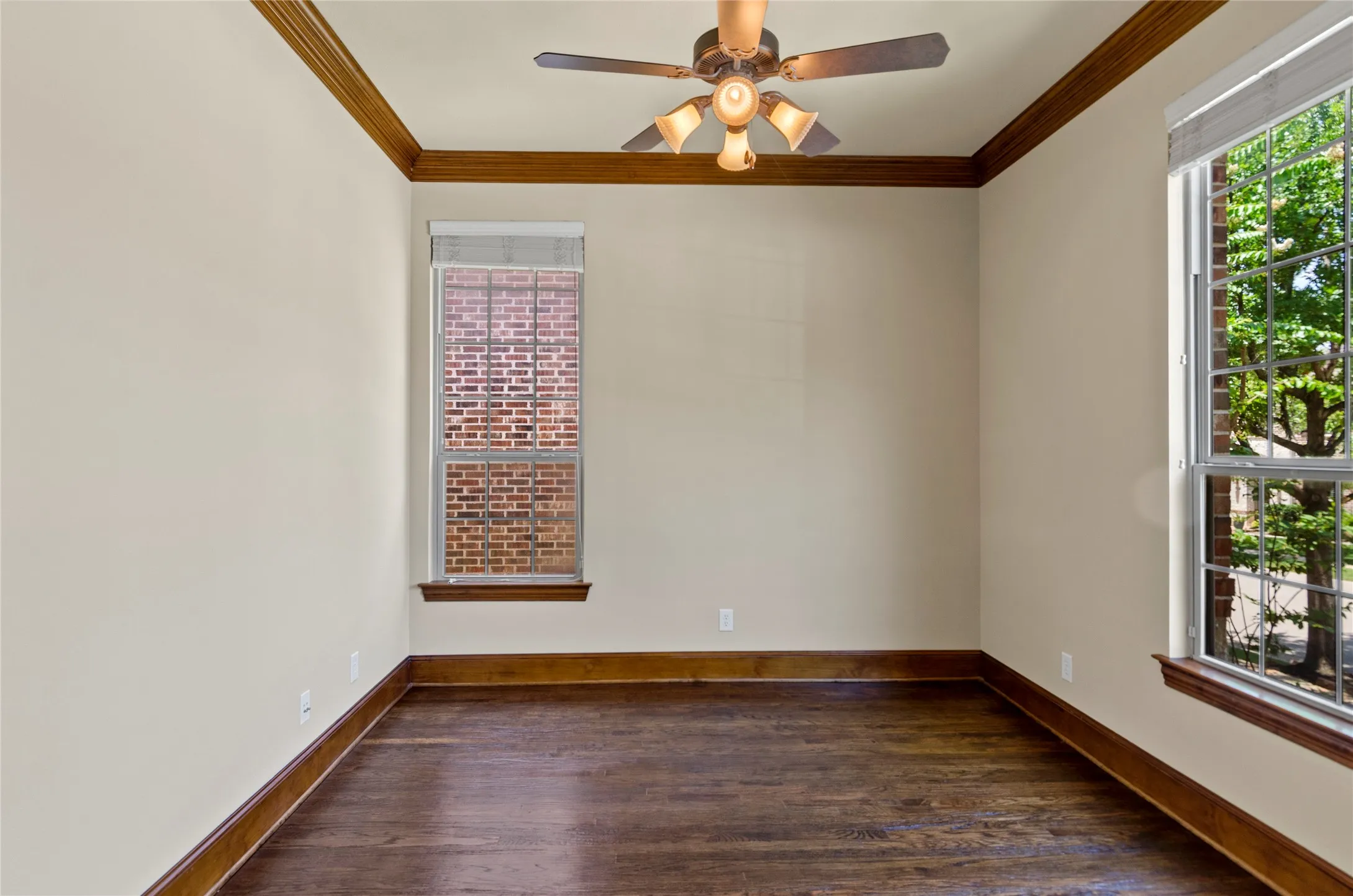 Room featuring dark wood-finish flooring, crown molding, and baseboards