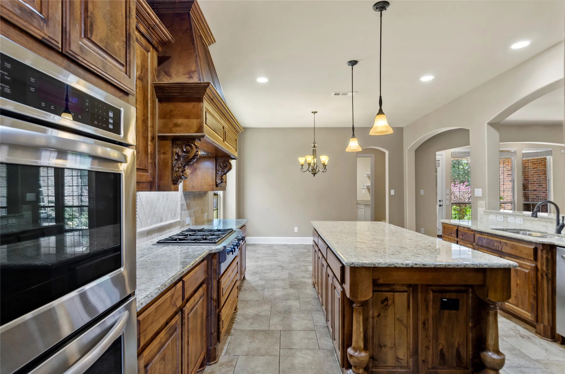 Kitchen featuring a large central island, granite countertops, stainless steel appliances, rich wood cabinetry, and recessed lighting