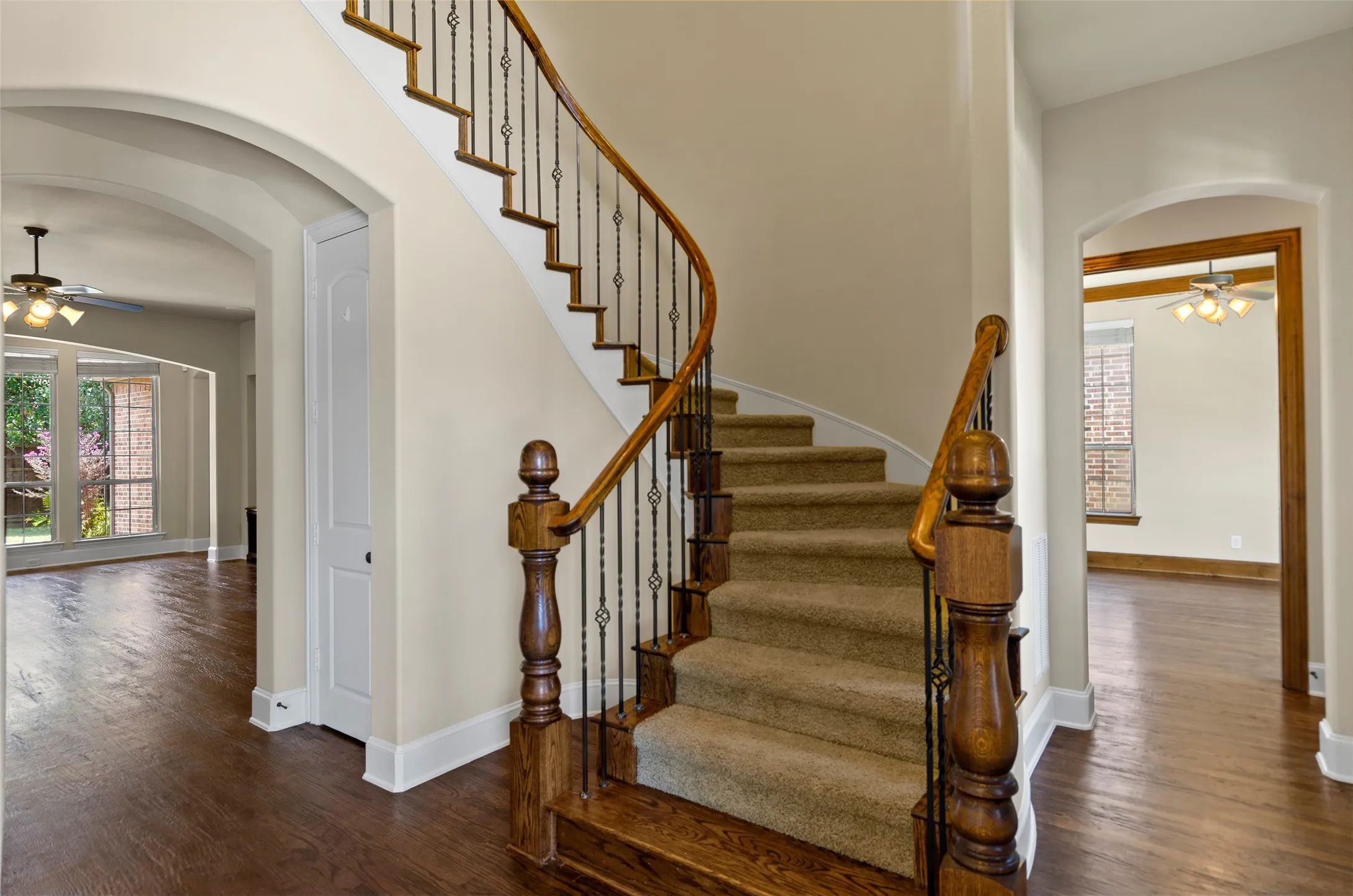 Curved staircase with wood-finish handrail and wrought iron spindles