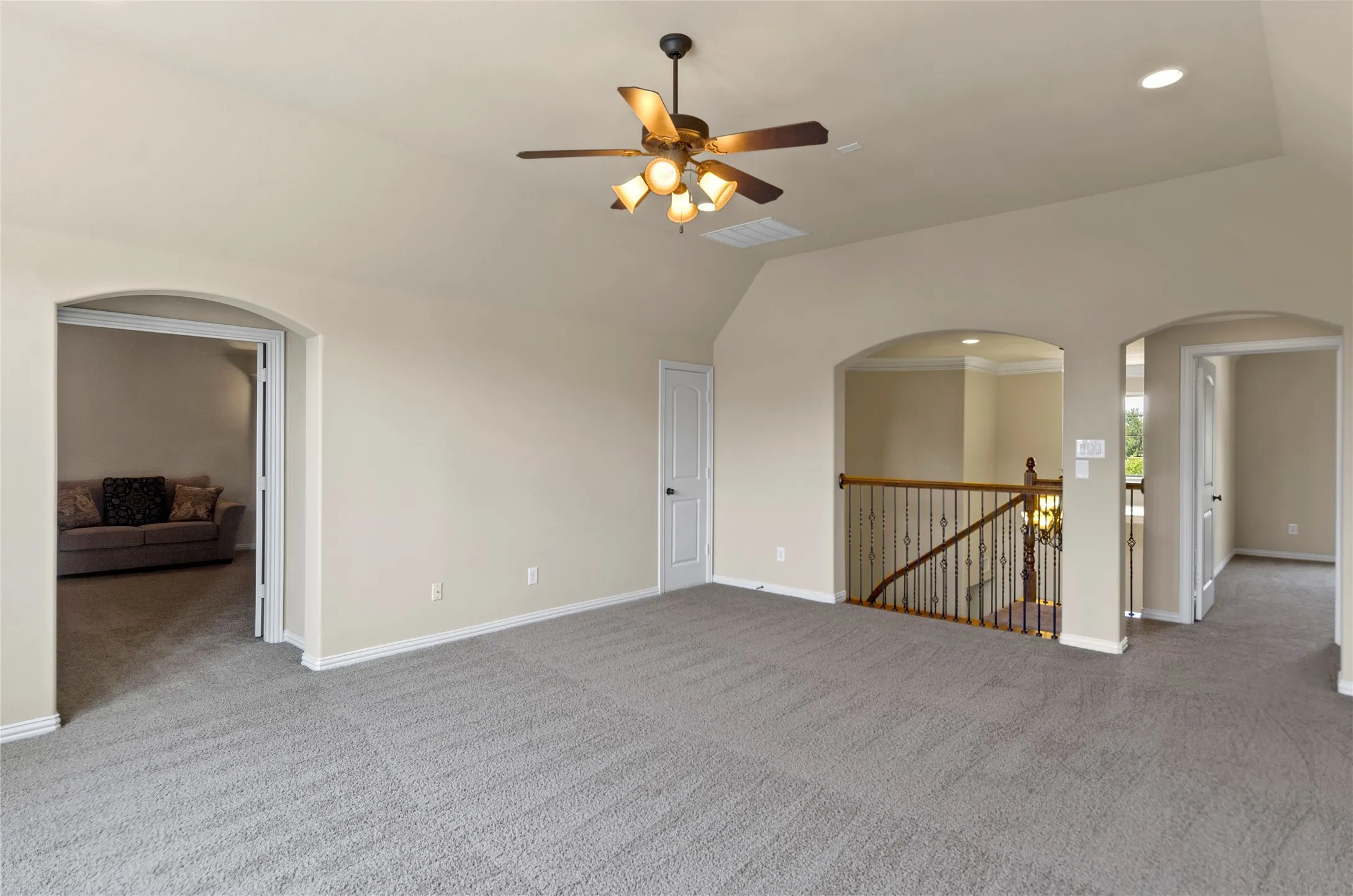 Spacious carpeted bonus room with vaulted ceiling and ceiling fan