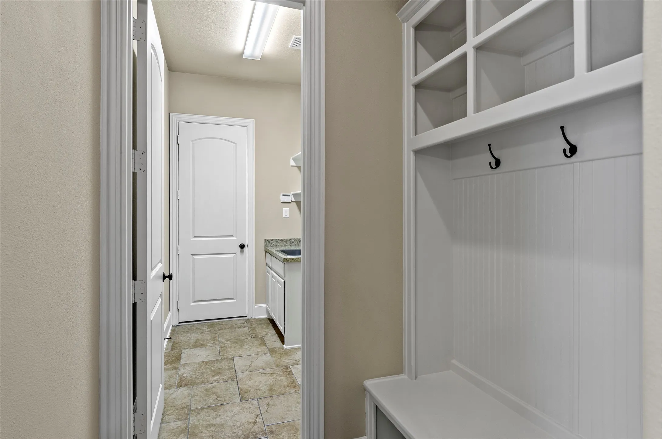 Built-in mudroom bench with cubbies and hooks, featuring beadboard paneling