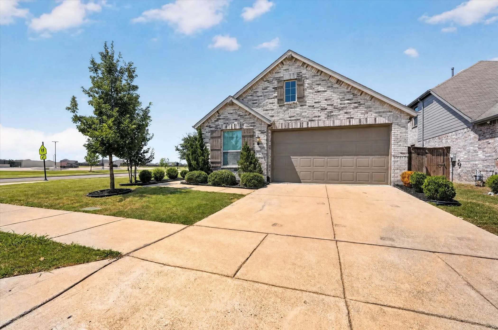 Brick facade home with an attached garage, landscaped front yard, and a concrete driveway
