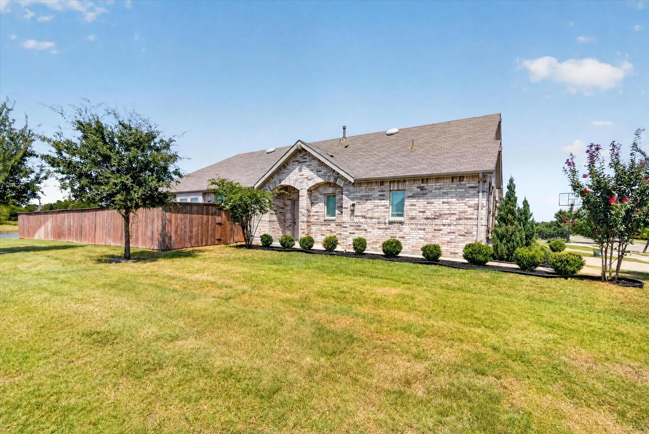 Stone exterior with pitched roof and multiple gable peaks, situated on expansive manicured lawn