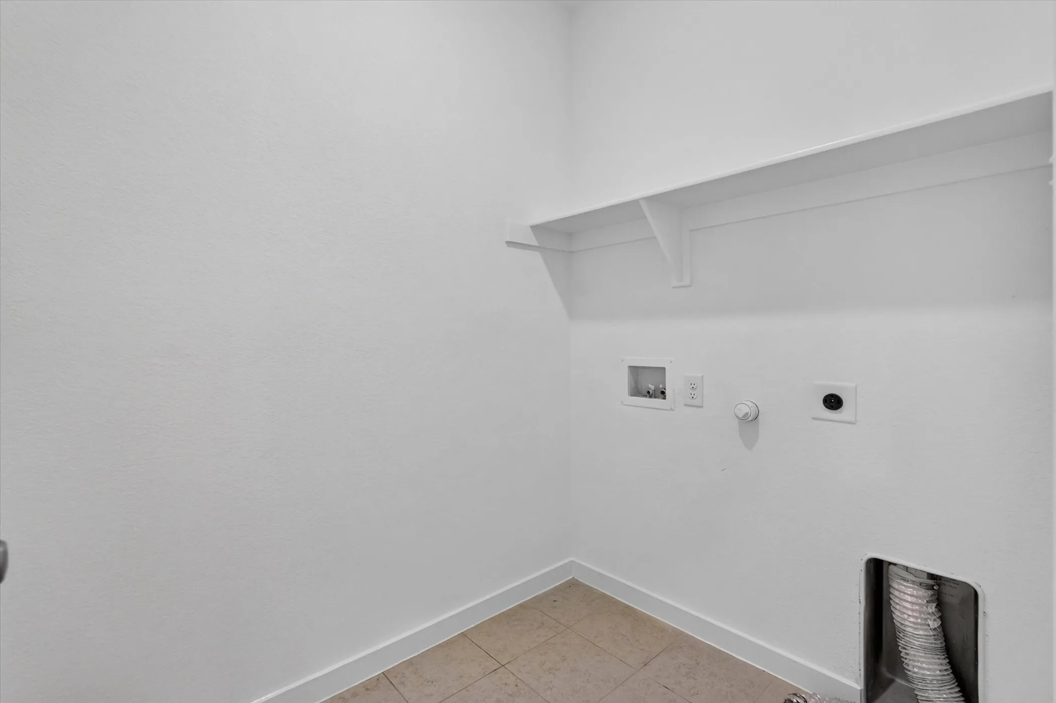 Utility room featuring clean white walls, polished concrete flooring, wall-mounted electrical outlets, and built-in shelving with integrated support brackets for efficient storage and organization